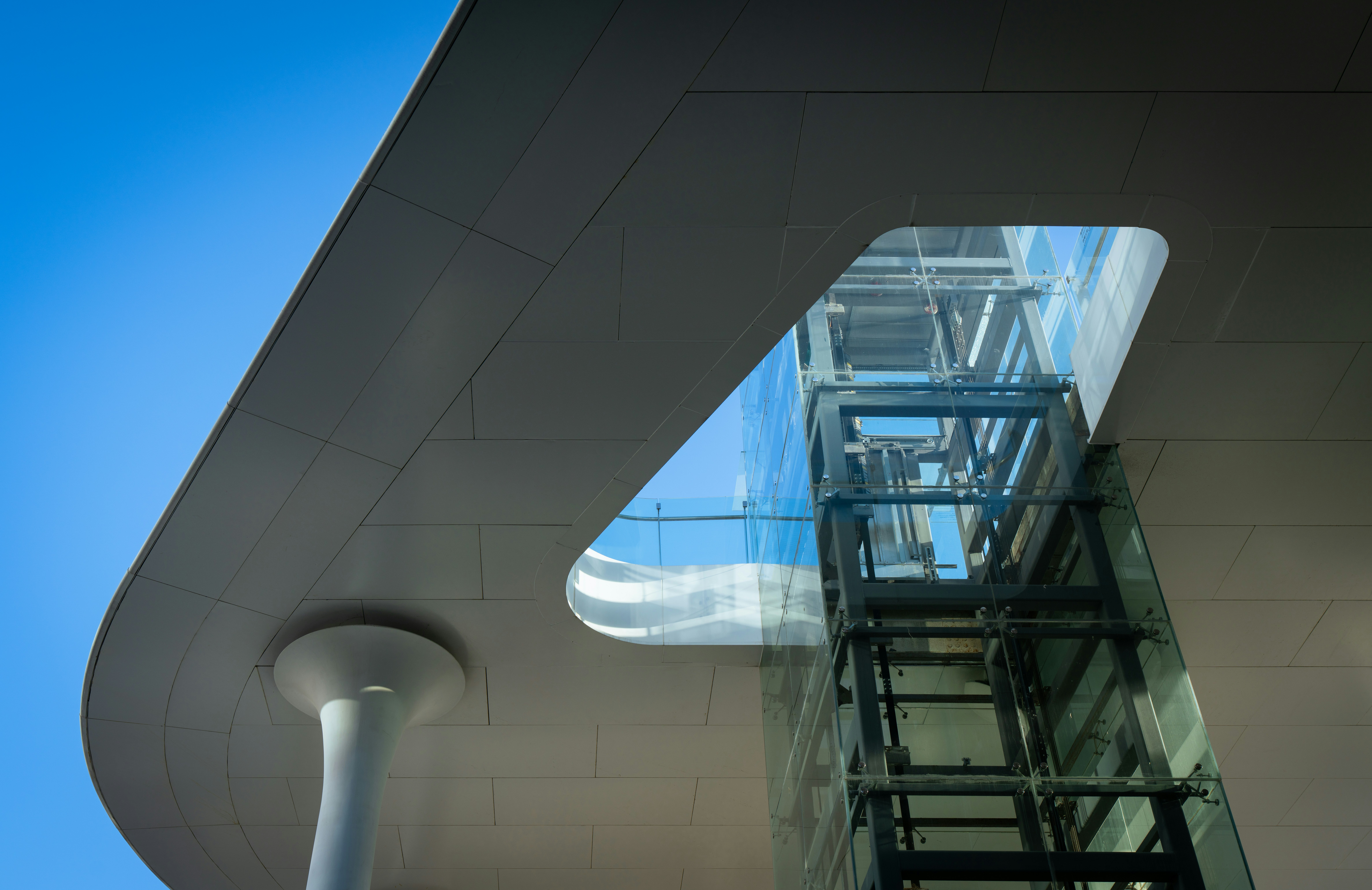 Modern building with glass elevator and blue sky