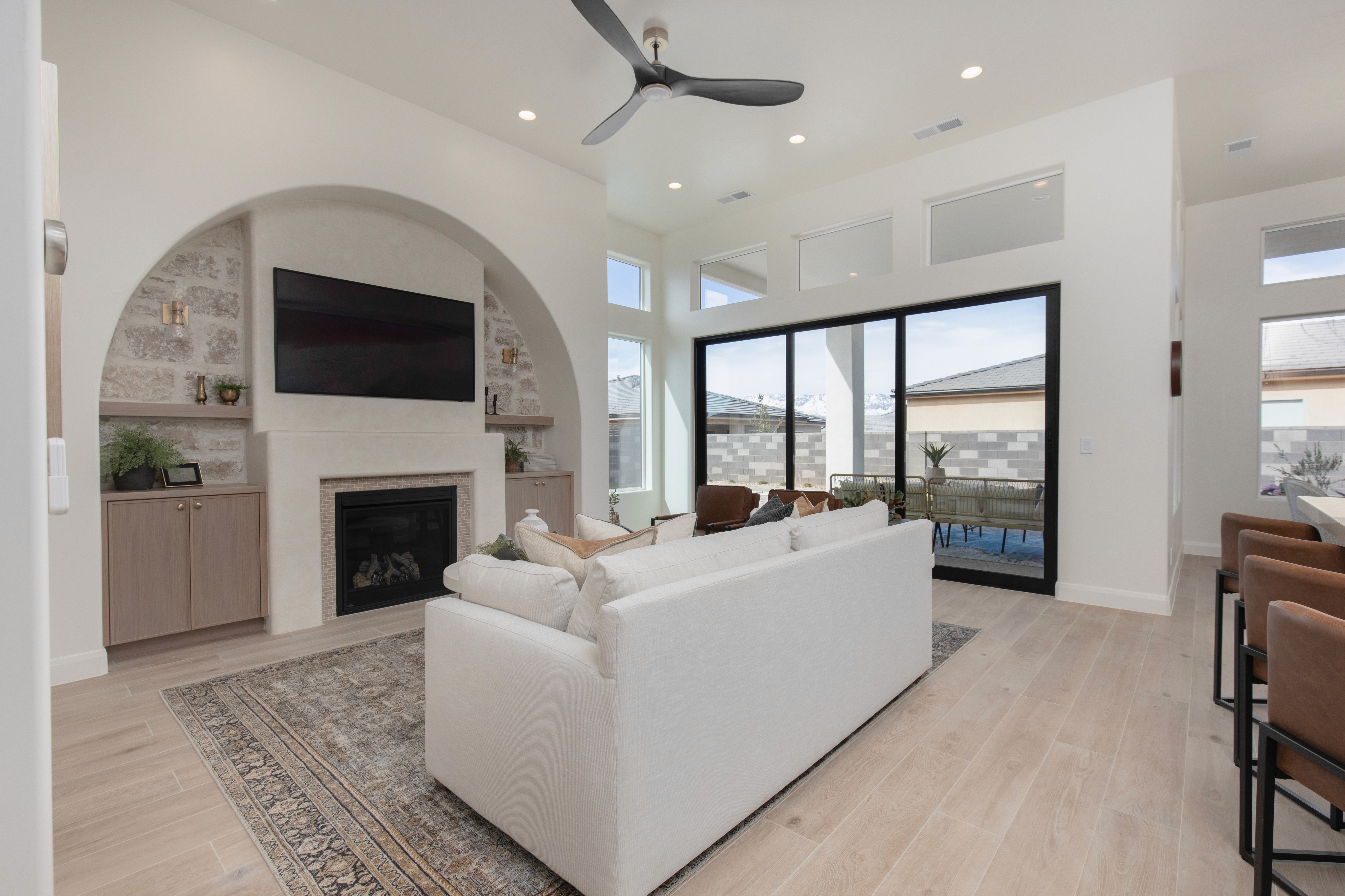 Living room in a custom home in Hurricane, Utah with an arch design over the fireplace, built in cabinetry, and open concept living.