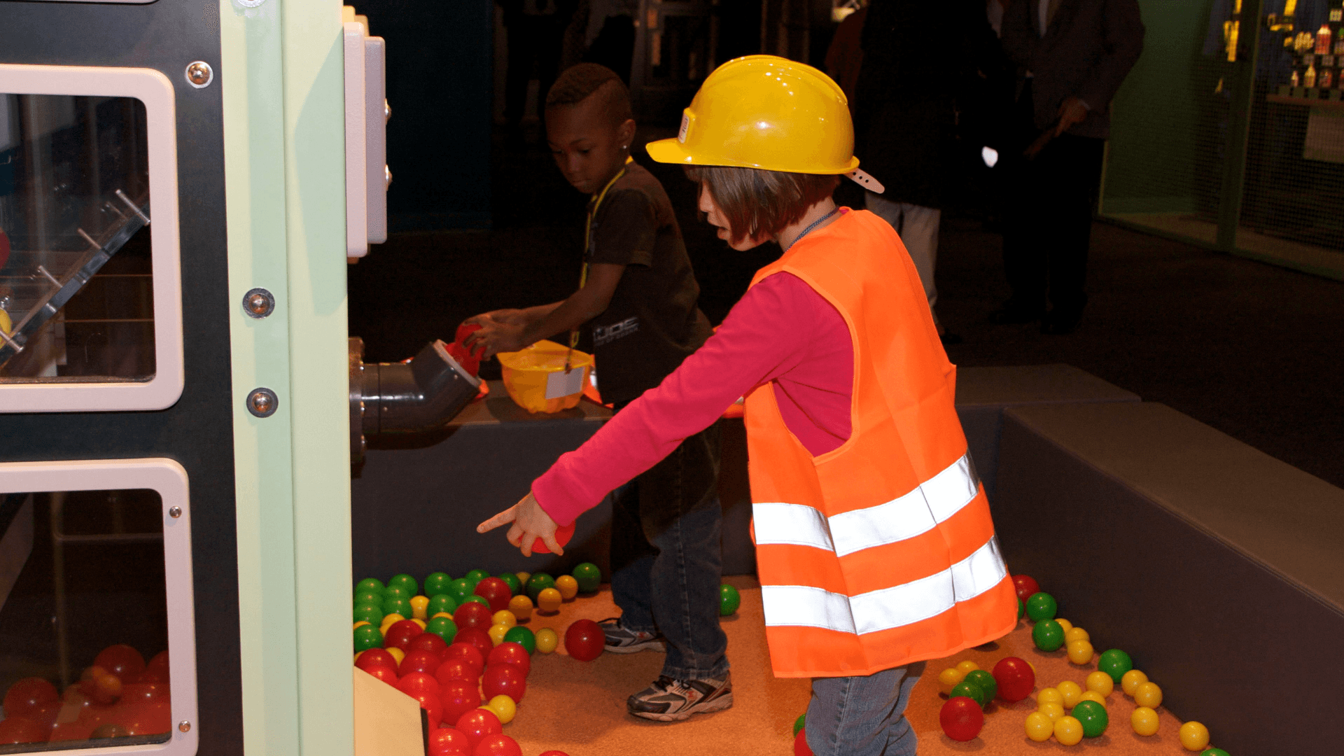 A young girl puts different colored balls that represent particles into the ball refinery.