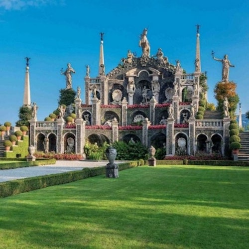 A grand ornate garden structure with statues, arches, and manicured hedges, set under a clear blue sky.