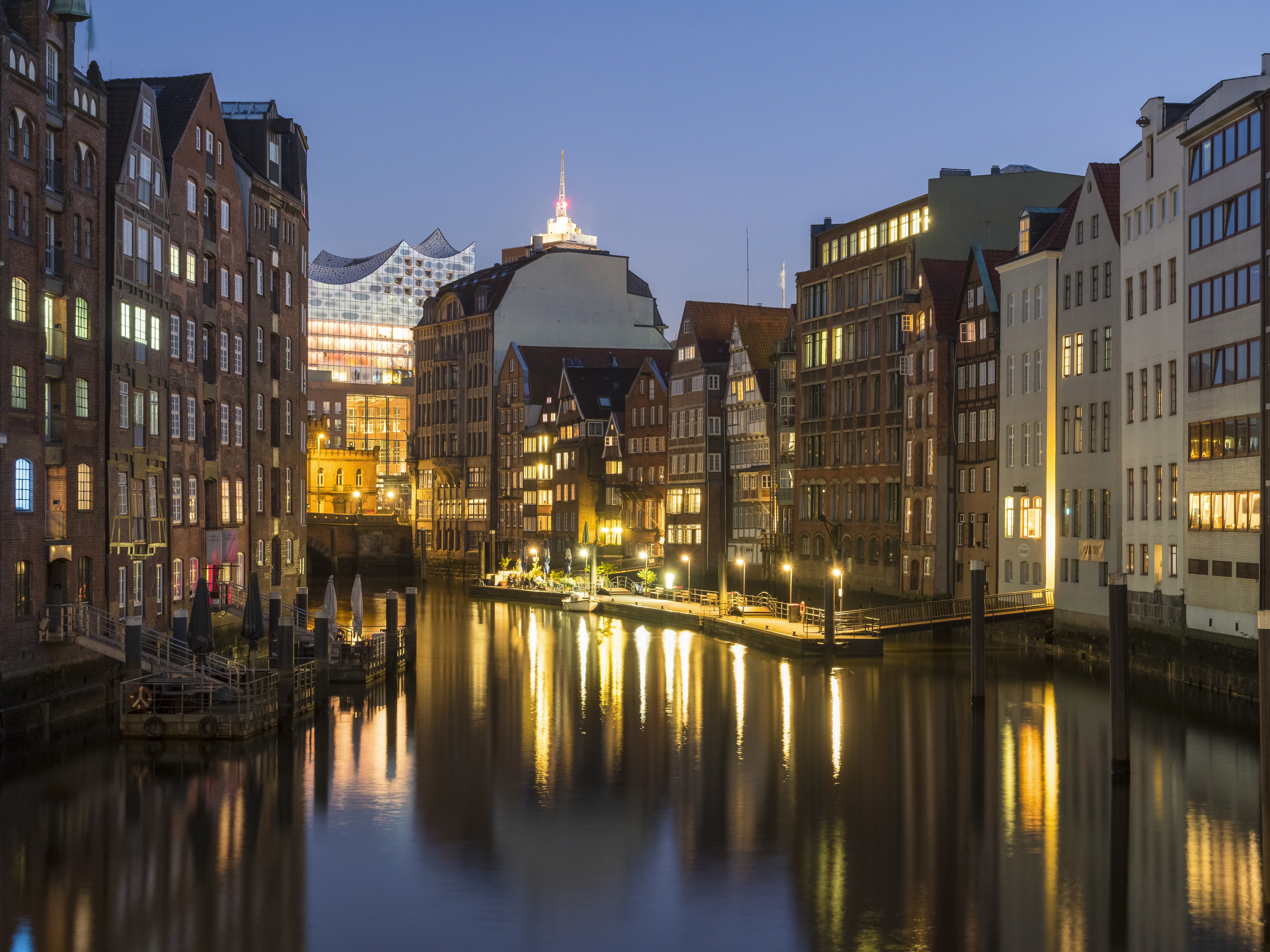 Hamburger Nikolaifleet bei Abenddämmerung mit beleuchteten Gebäuden und Blick auf die Elbphilharmonie