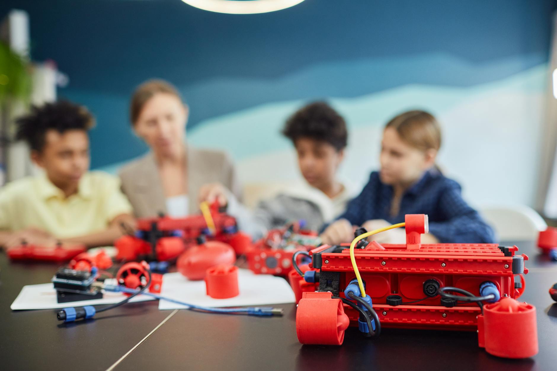 Two middle school students smiling while assembling a small programmable robot at a desk with a laptop.