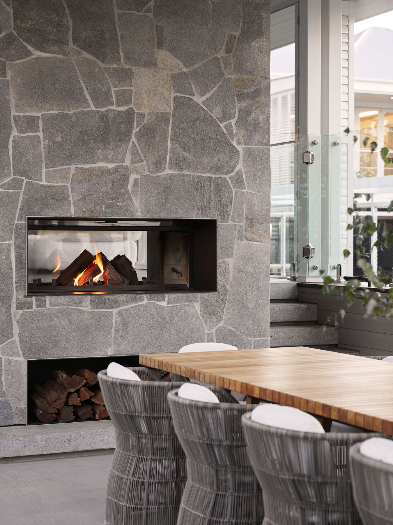 dining setting with stone fireplace, timber table and woven seating
