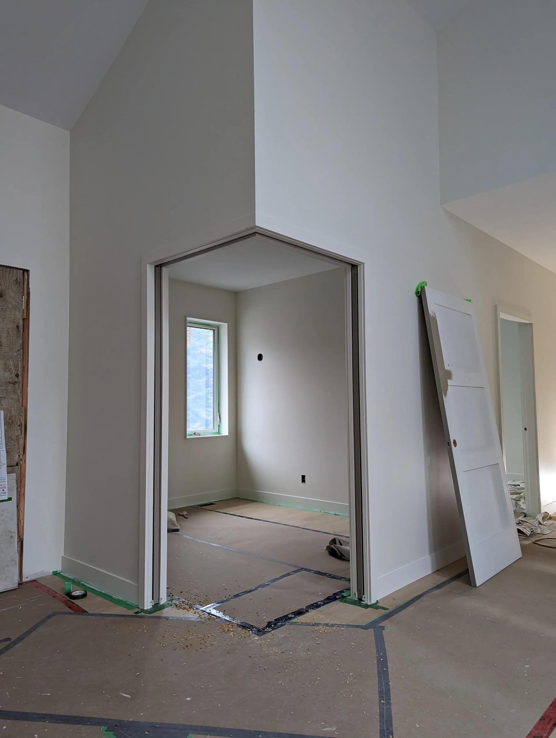 Modern two-story home with large glass windows, warmly lit interiors, and a balcony. Surrounded by trees and a manicured lawn at dusk. Cozy ambiance.