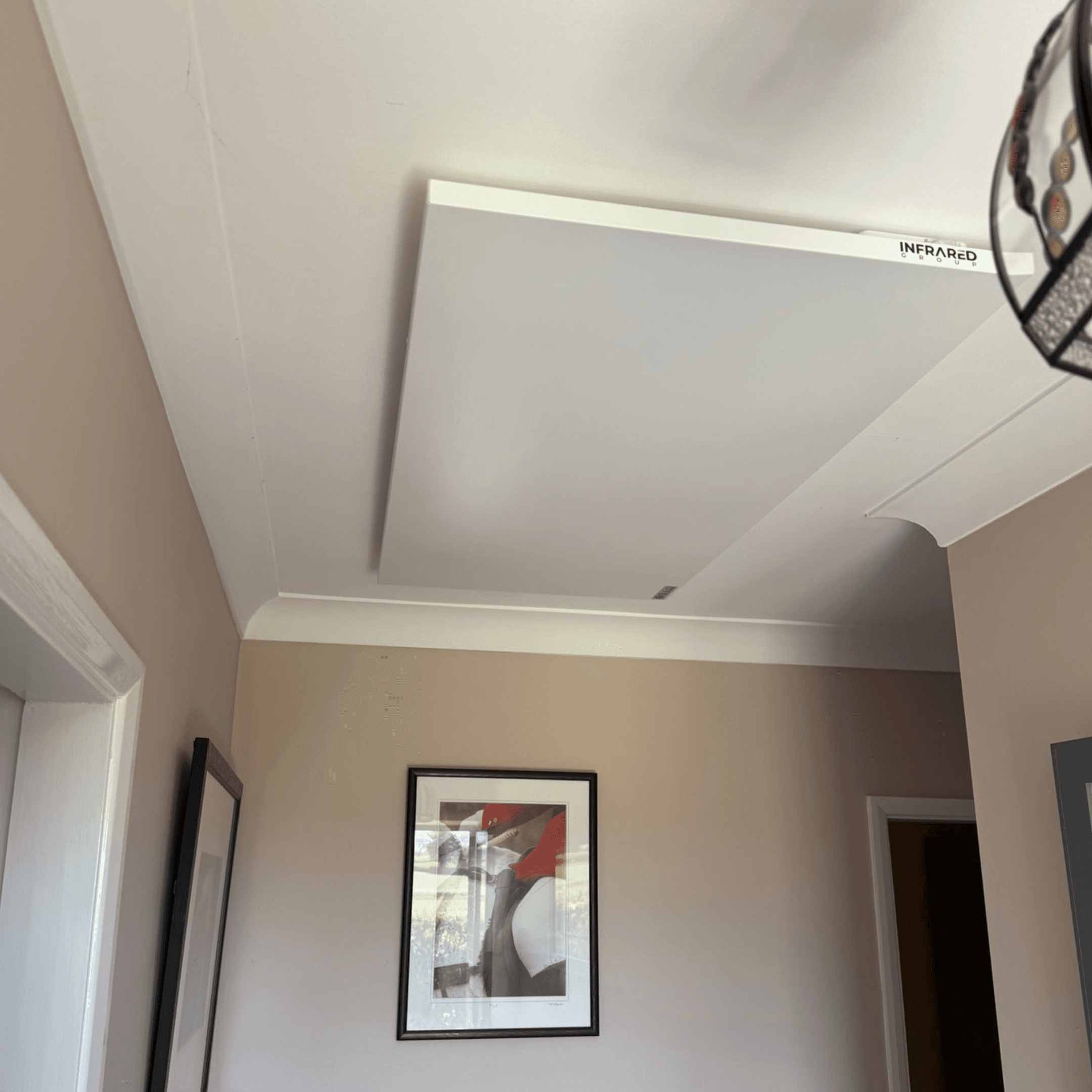 A photo of a clean doctors surgery treatment room with a white, wall mounted infrared panel behind the treatment bed.