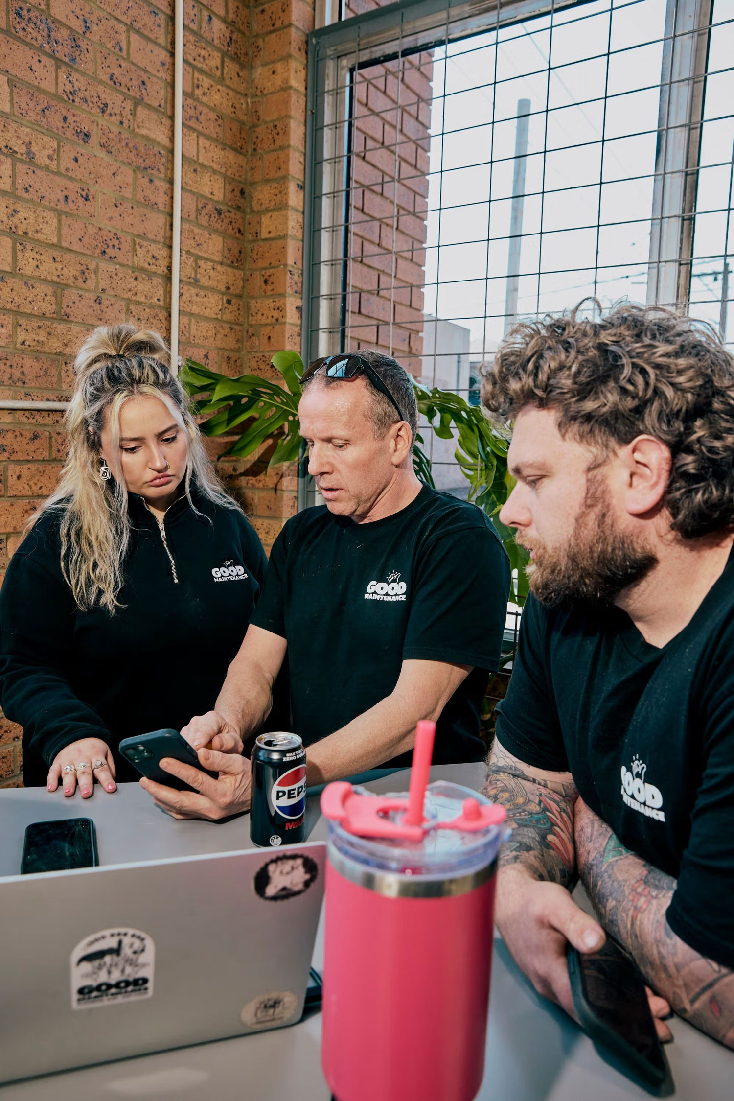 Team members collaborating at a table using a laptop and mobile phones.