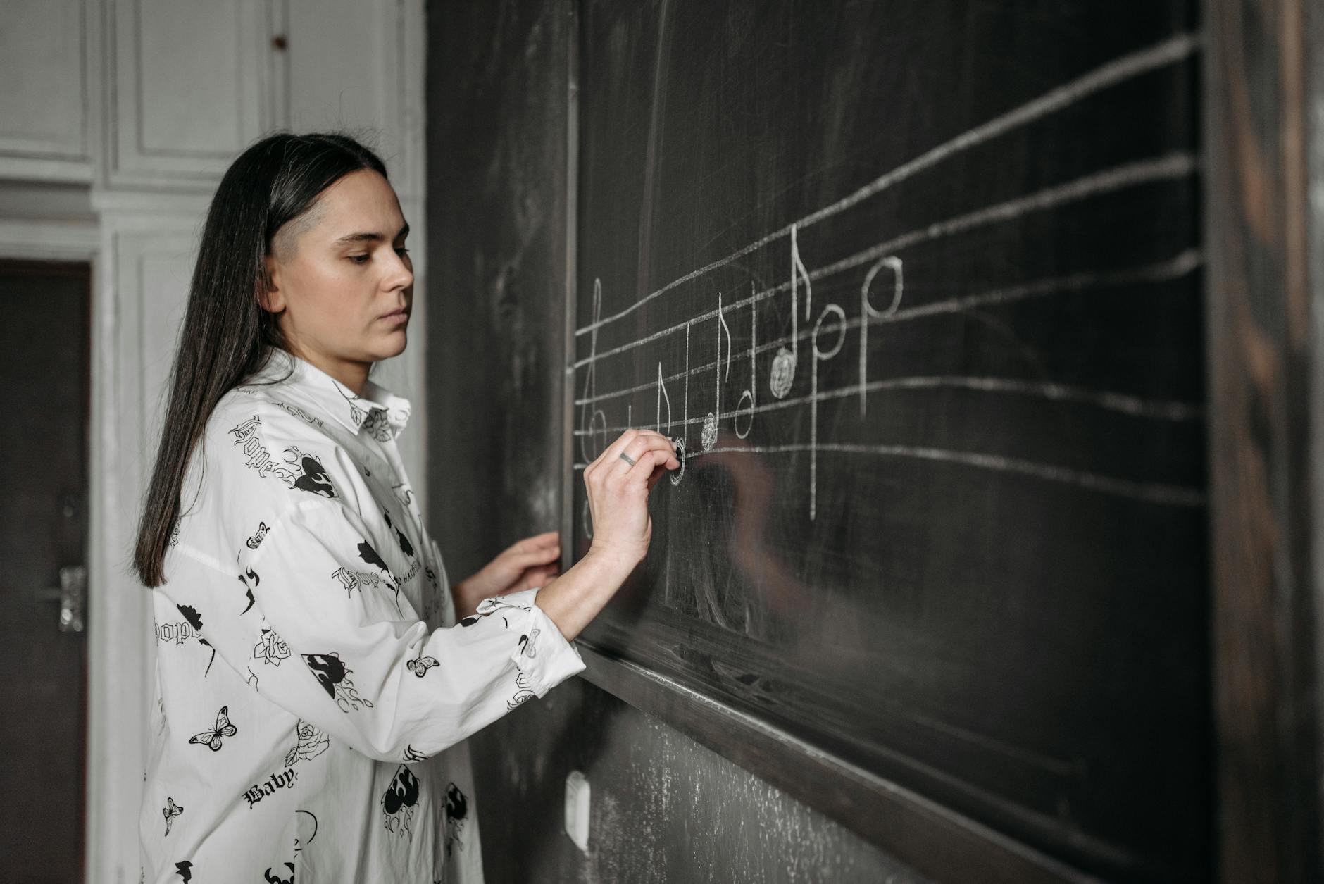 A smiling teacher stands at a whiteboard leading a professional development seminar for school staff.