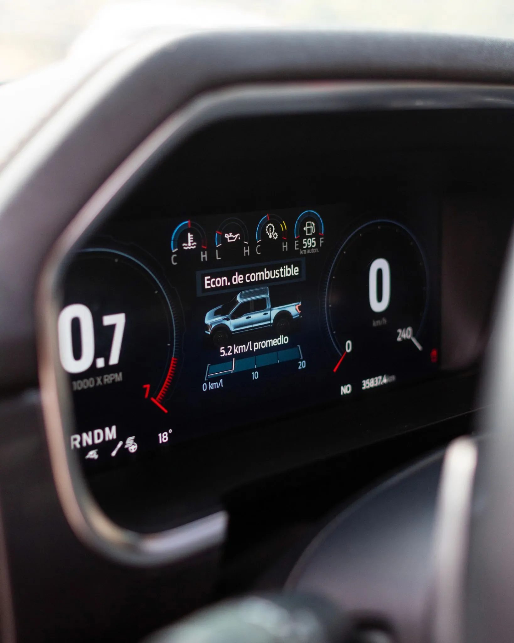 Interior de Ford F-150 Raptor naranja con volante deportivo, pantalla central y consola