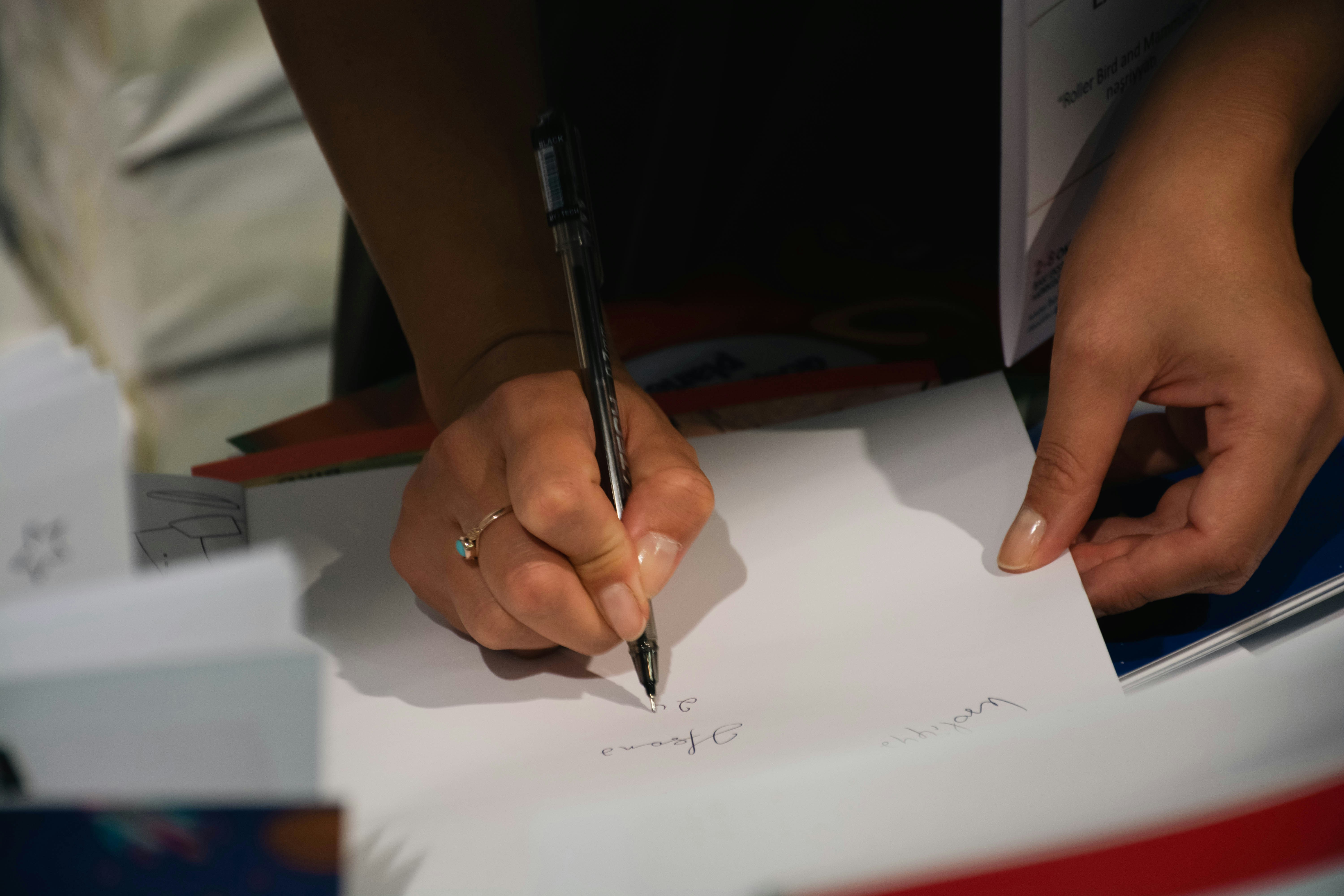 Person signing a paper with a pen.