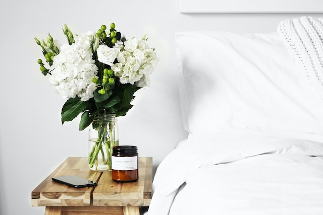 bedside table with flowers in a vase and a jar with facecream