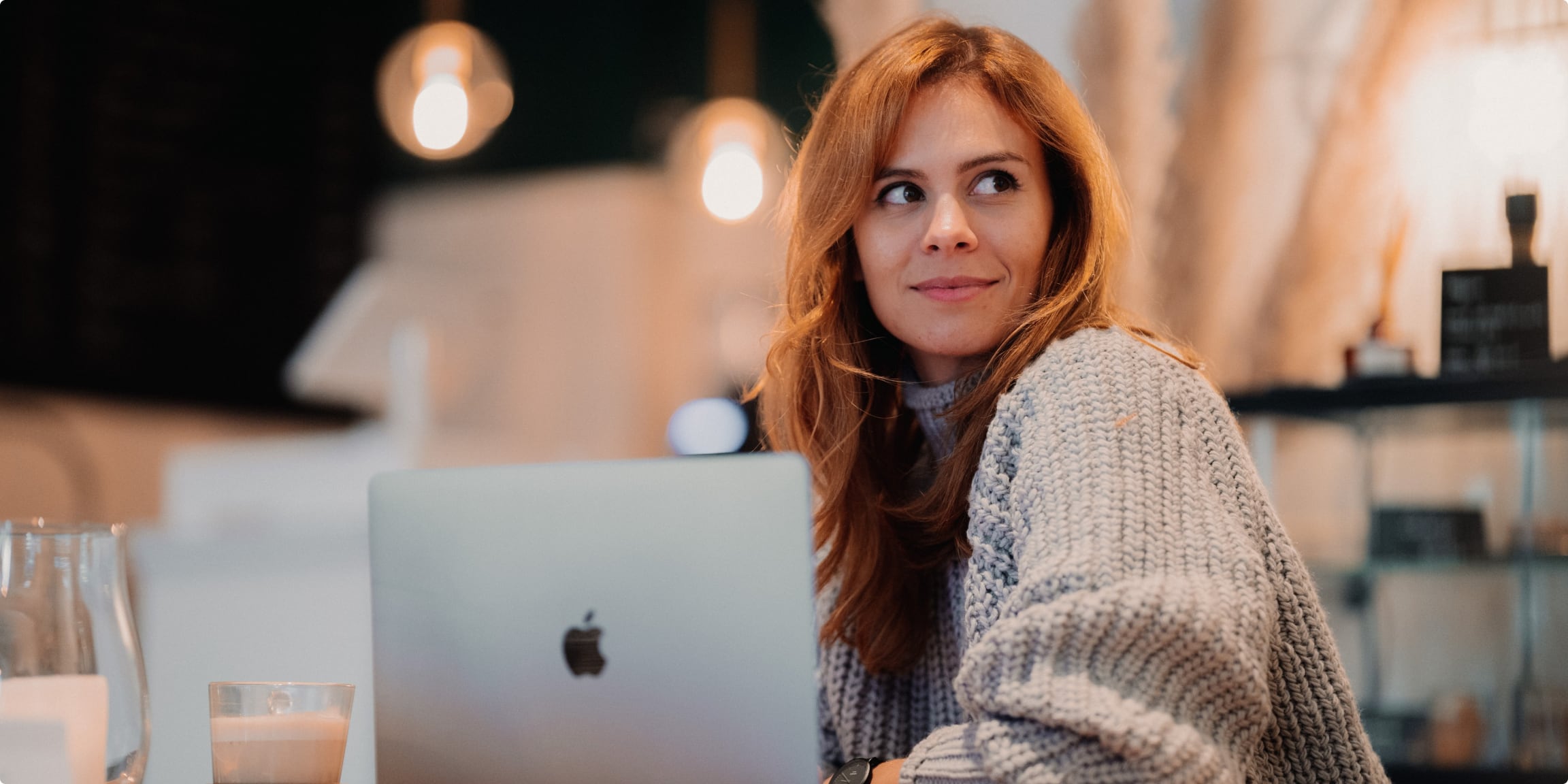 Decorative image of a woman with a laptop computer looking off camera with a confident smile.