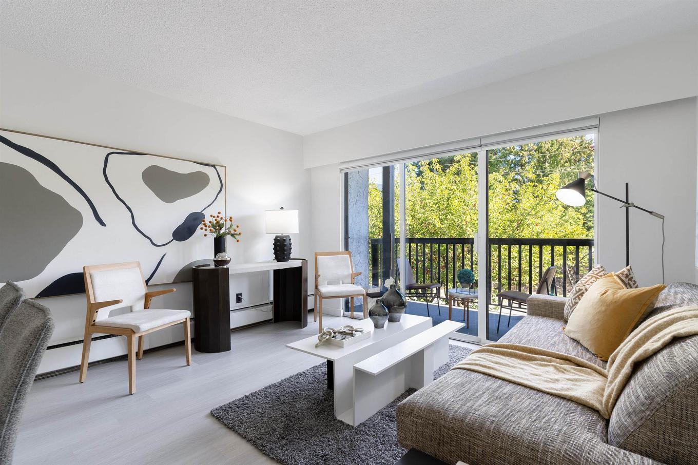 Modern living room with large windows, minimalist furniture, and soft colors. Natural light brightens the space.