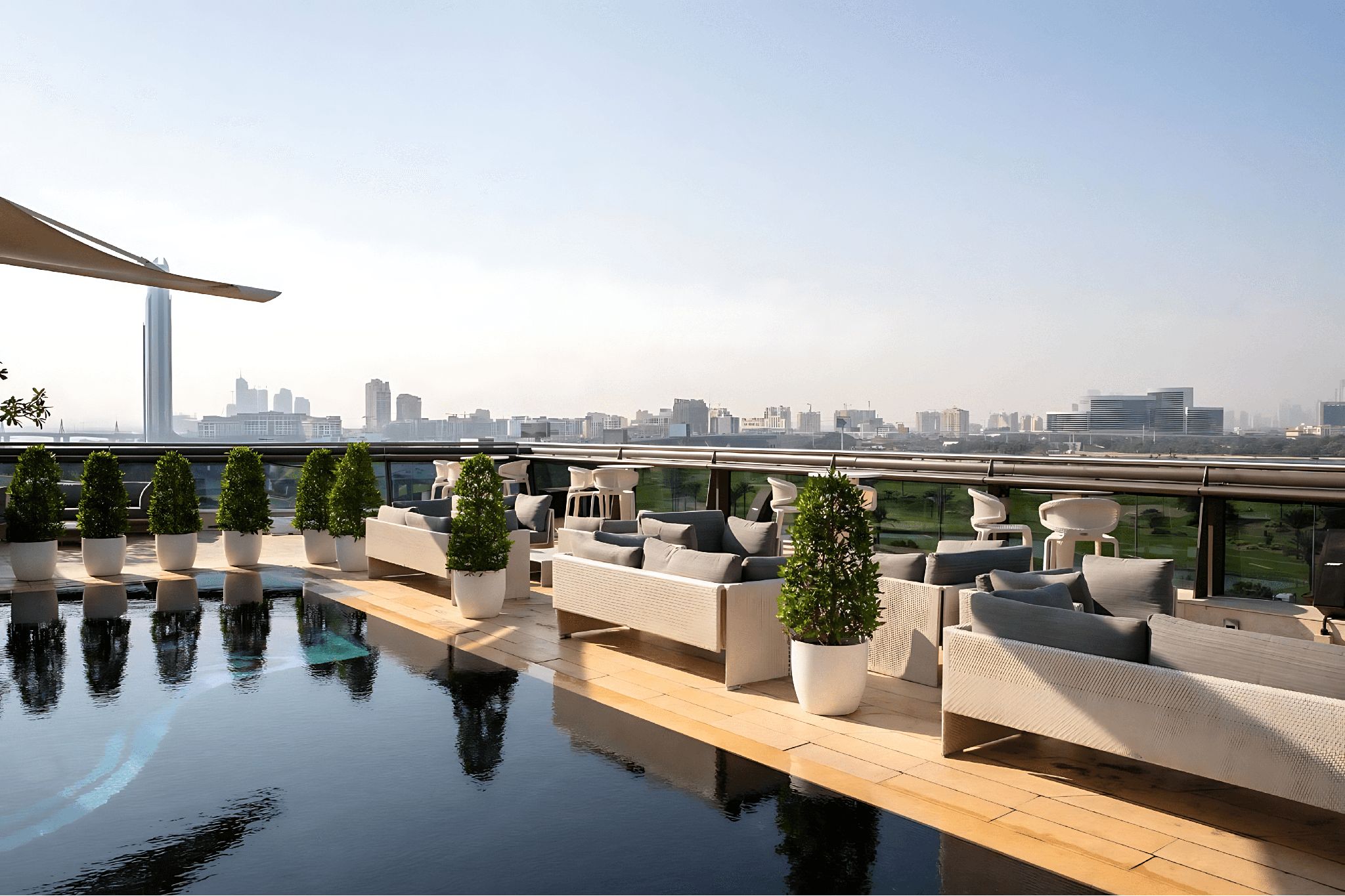 The outdoor poor of Jumeirah Creekside Hotel, with outdoor seating, tables, and green plants.