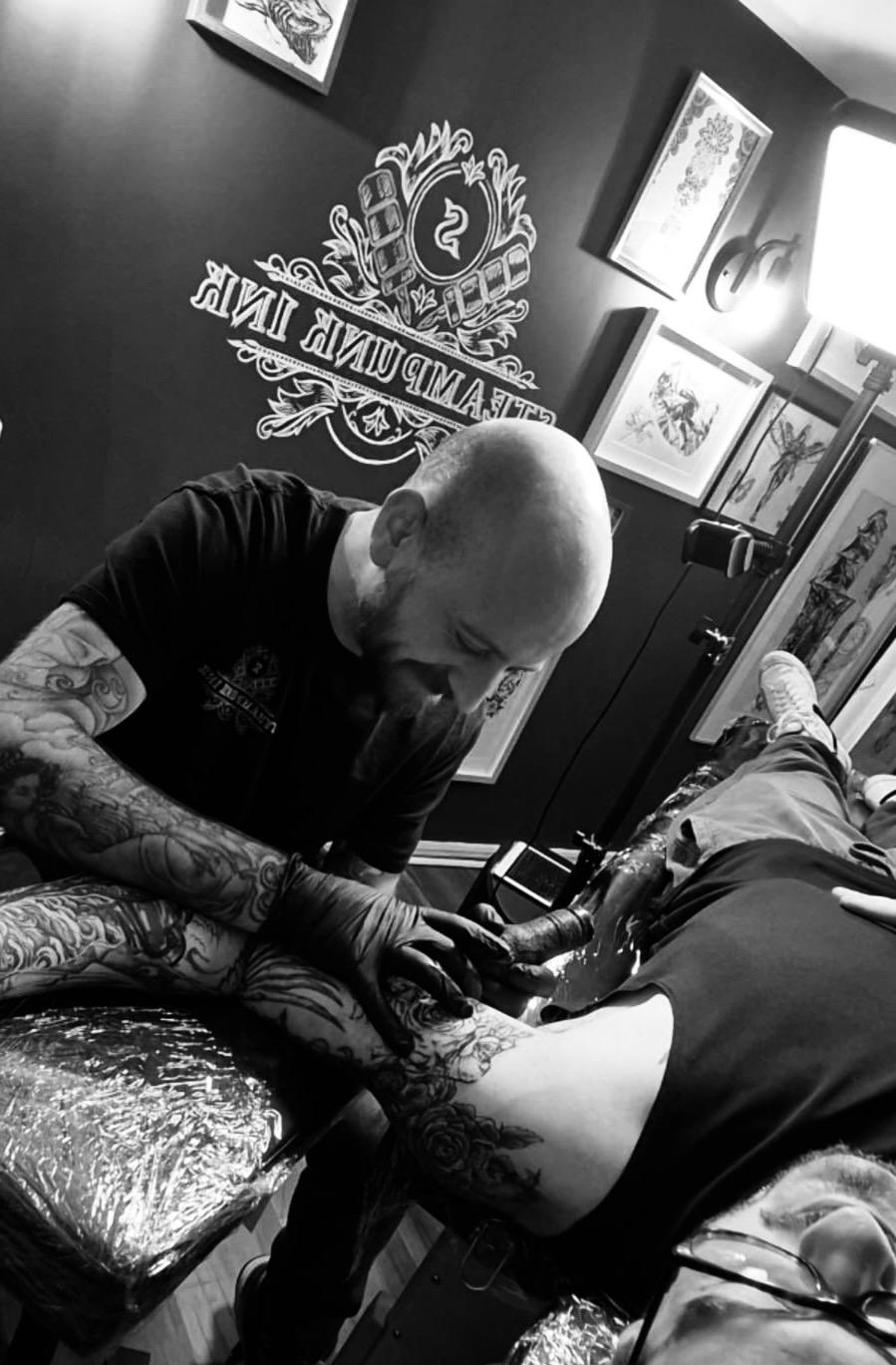 Tattoo artist working on client in studio at Hazel Grove