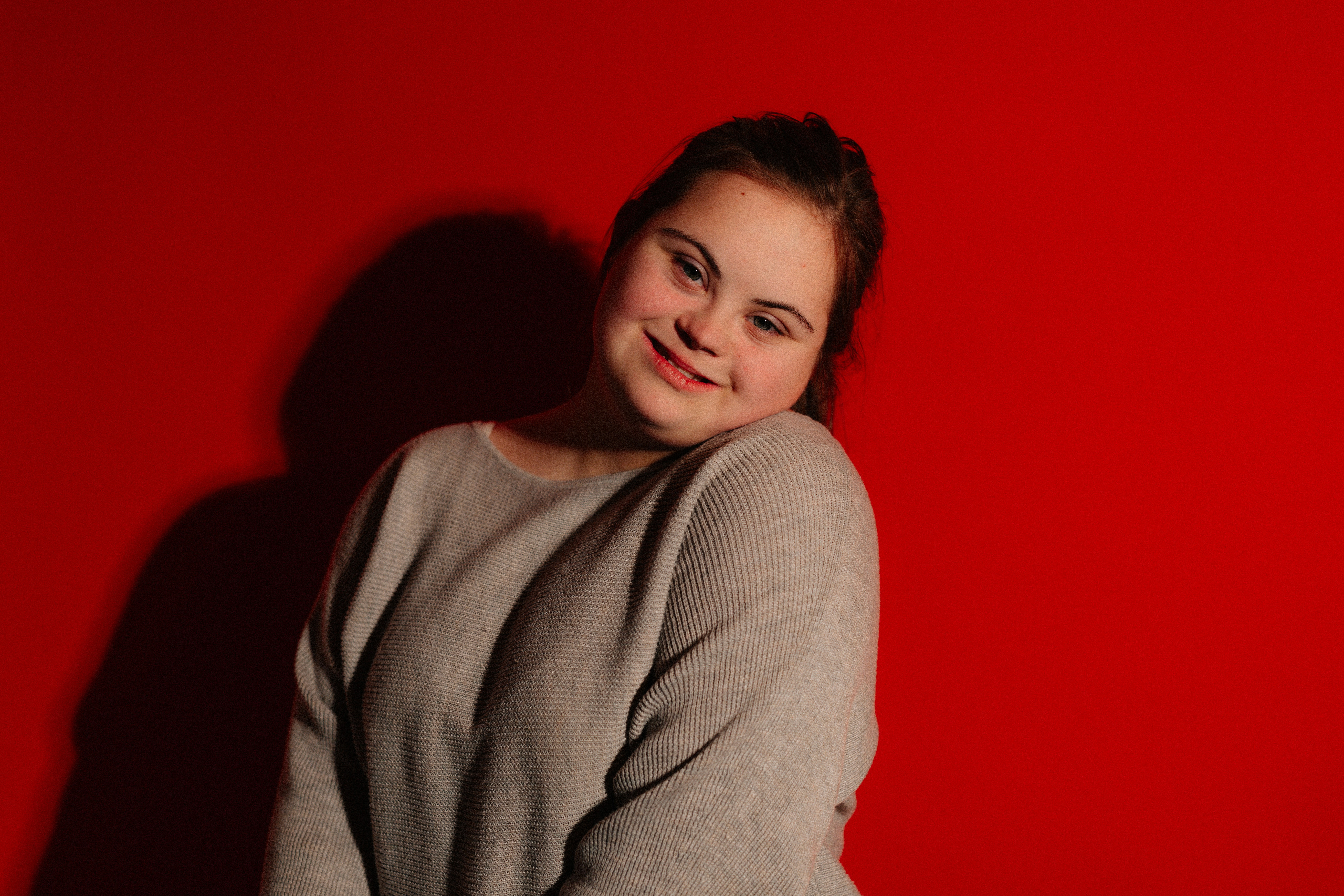 A young woman with down syndrome smiles warmly.