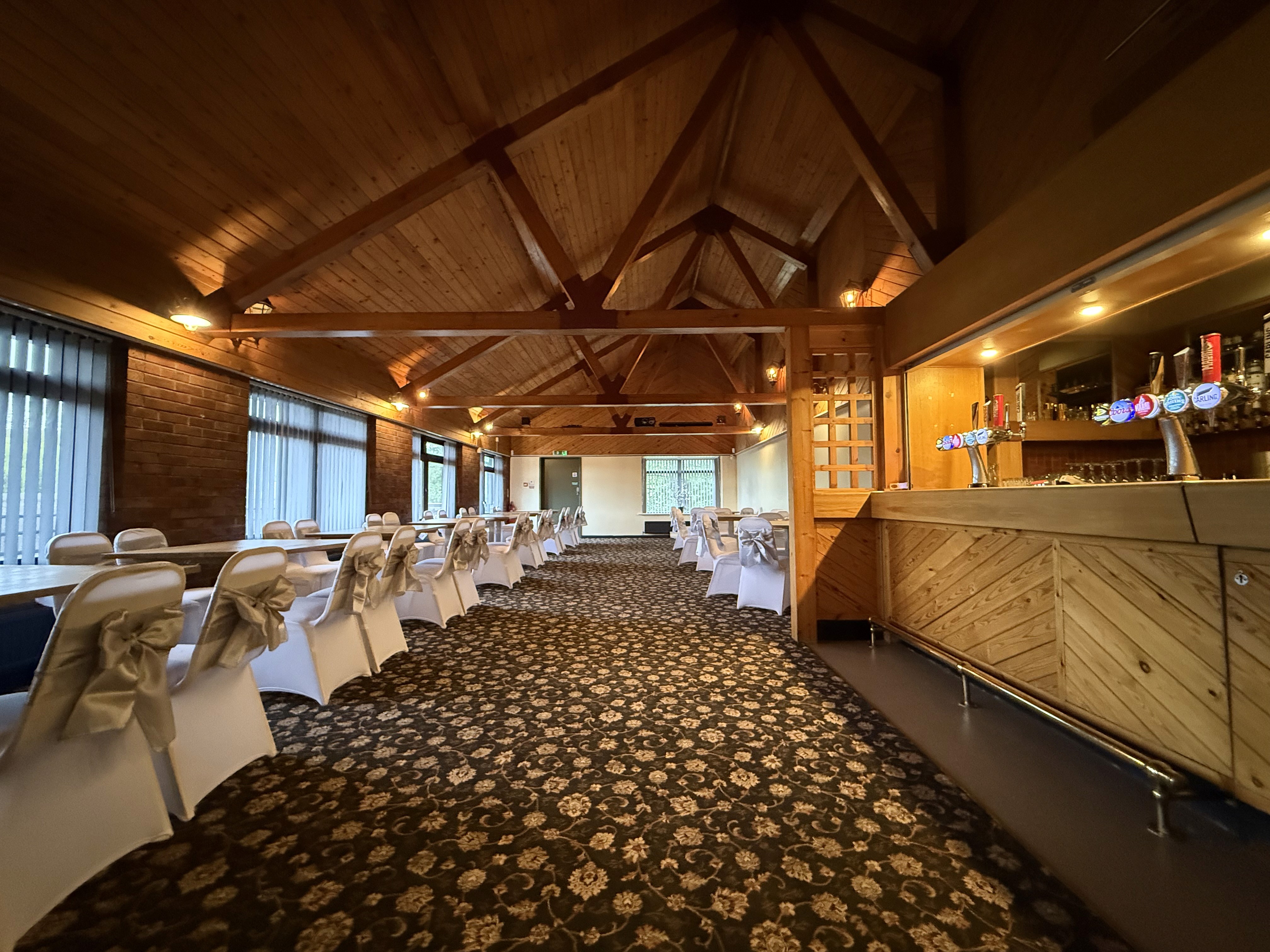Function room with open ceiling and furniture to left bar to right