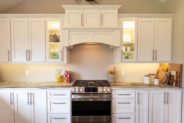 Farmhouse range hood and stove with white kitchen cabinets