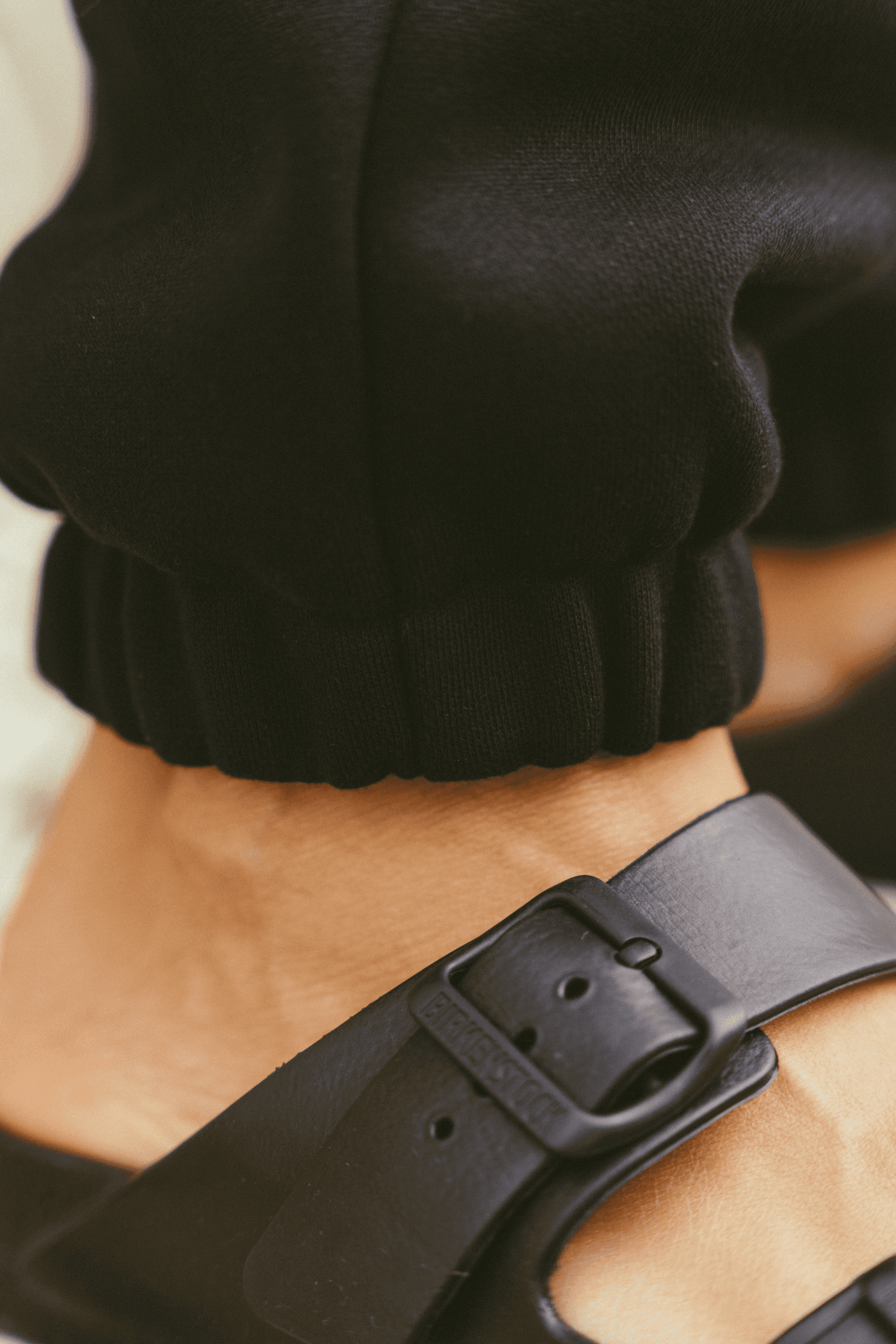 Close-up-of-a-person-wearing-black-joggers-with-elastic-cuffs-paired-with-black-birkenstock-sandals