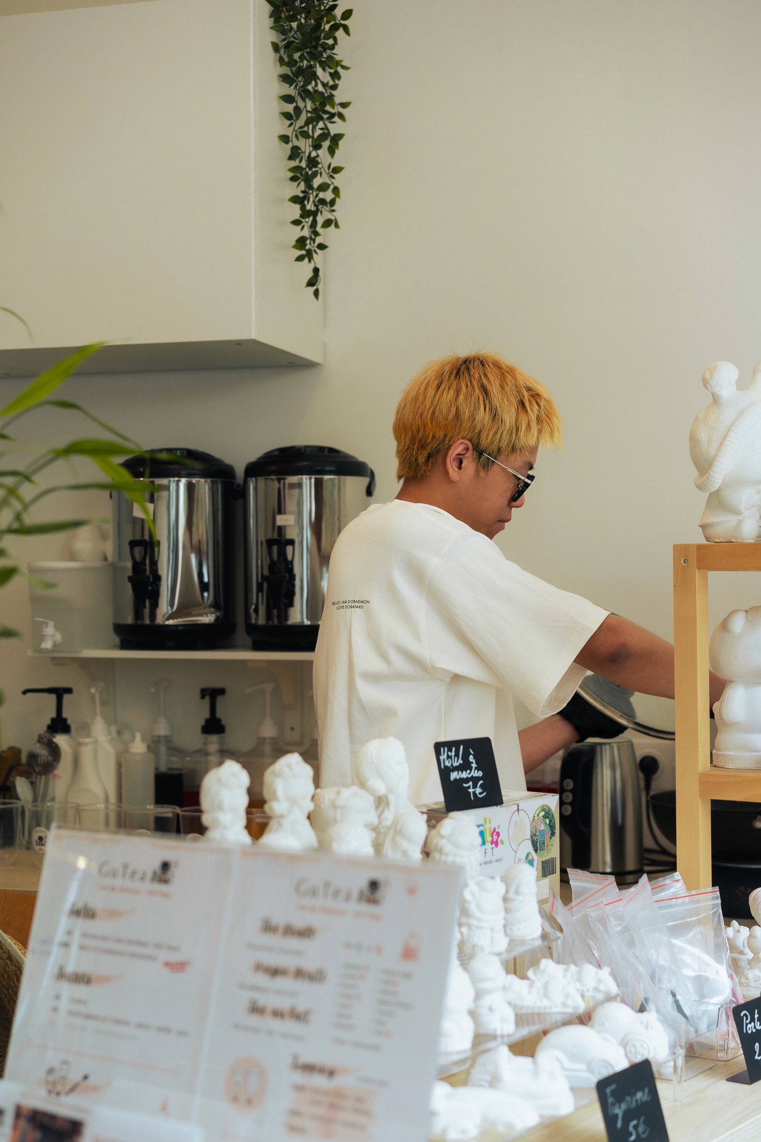 Scène intérieure de GUTEA Paris 13e, avec le patron concentré et des objets artisanaux exposés.