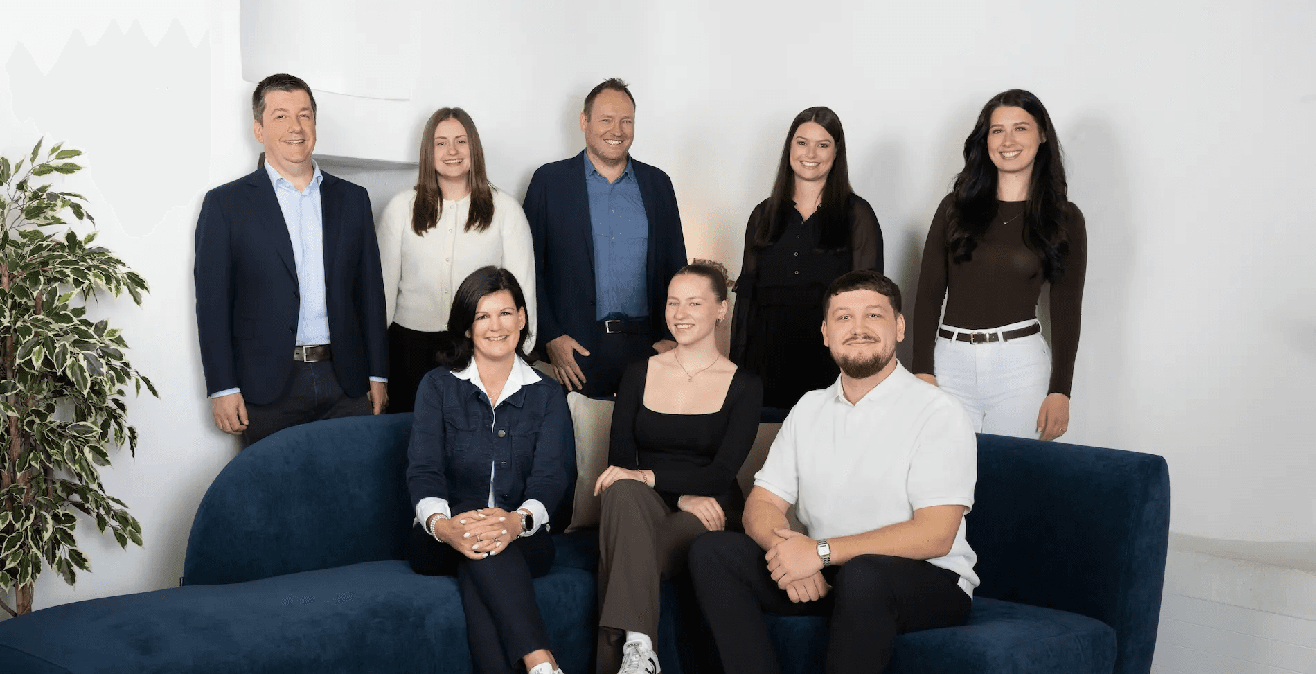 Gesamtes Team von Kocher Immobilien sitzt gemeinsam im Büro und lacht in moderner Umgebung