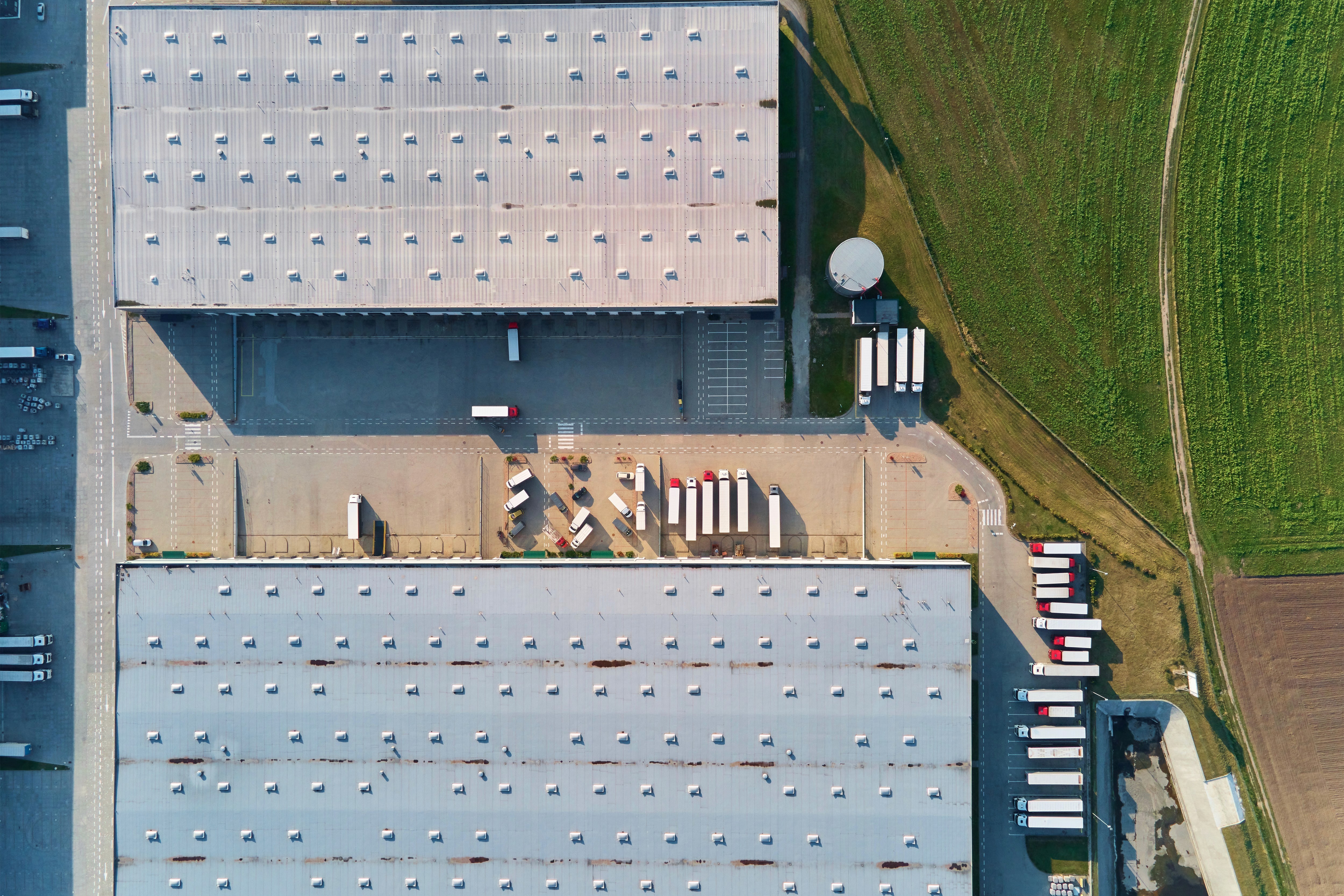 Aerial view of large logistics warehouse and freight trucks at loading docks