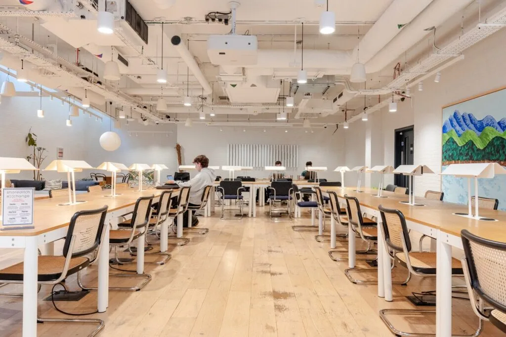 Members working at long shared desks in Arada’s Shoreditch Exchange coworking space.
