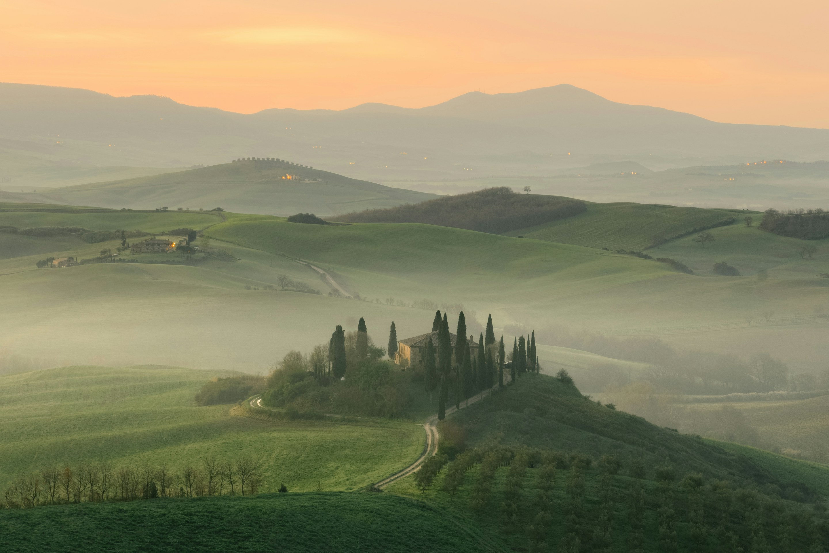 Misty golden sunrise over Tuscan vineyard hills