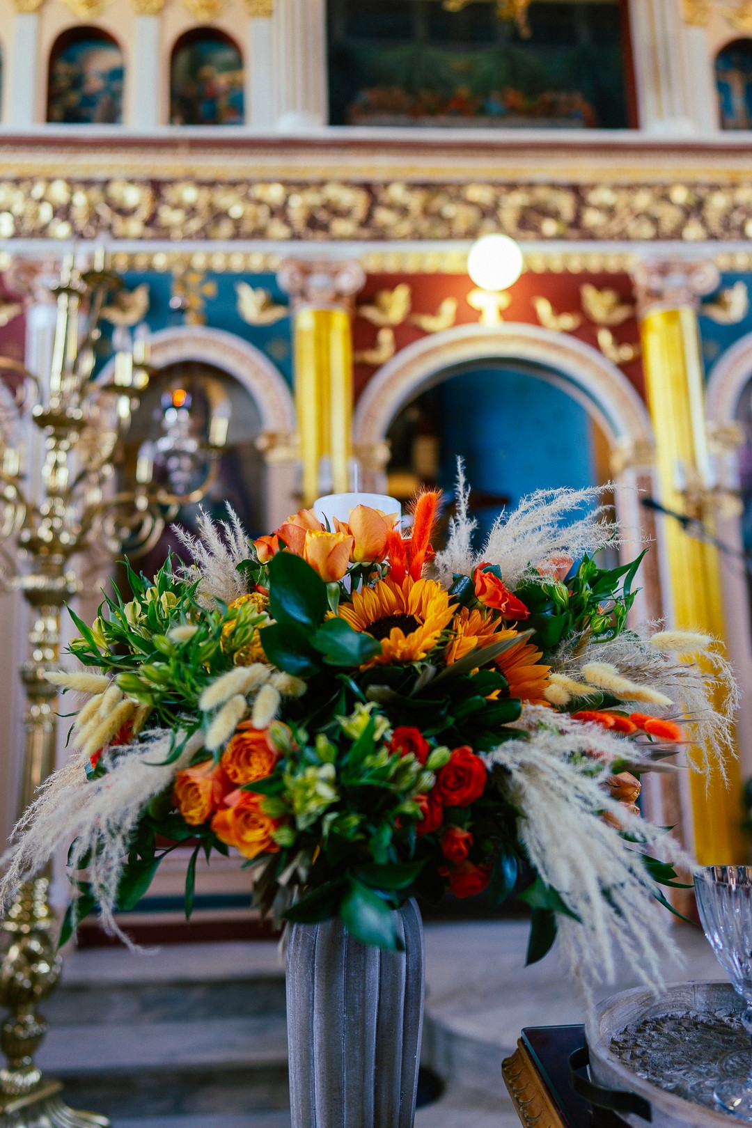 Πολύχρωμος στολισμός λαμπάδας γάμου με ηλιοτρόπια και έντονα λουλούδια