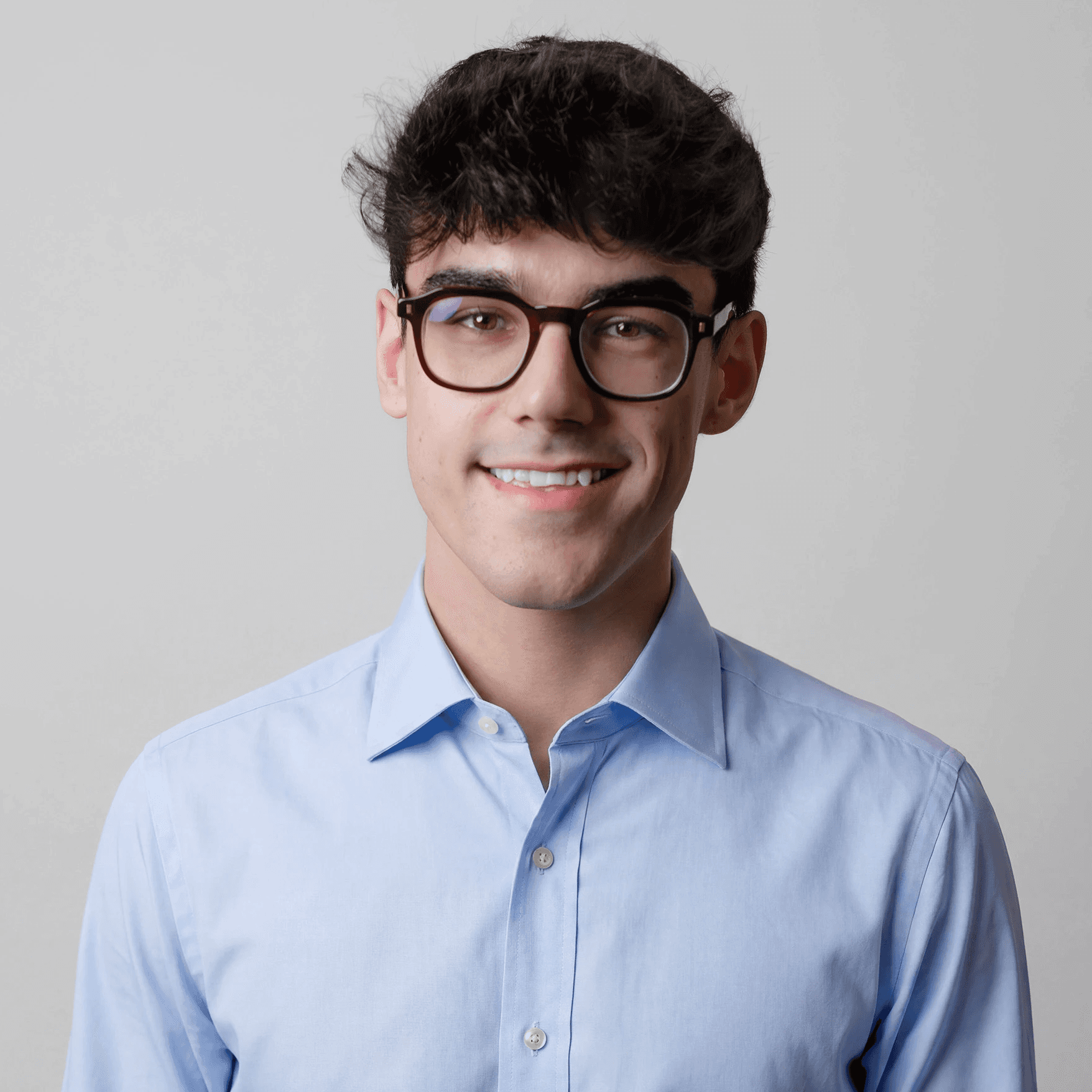 A thoughtful young person with dark hair gazes to the side, captured in soft black and white lighting.
