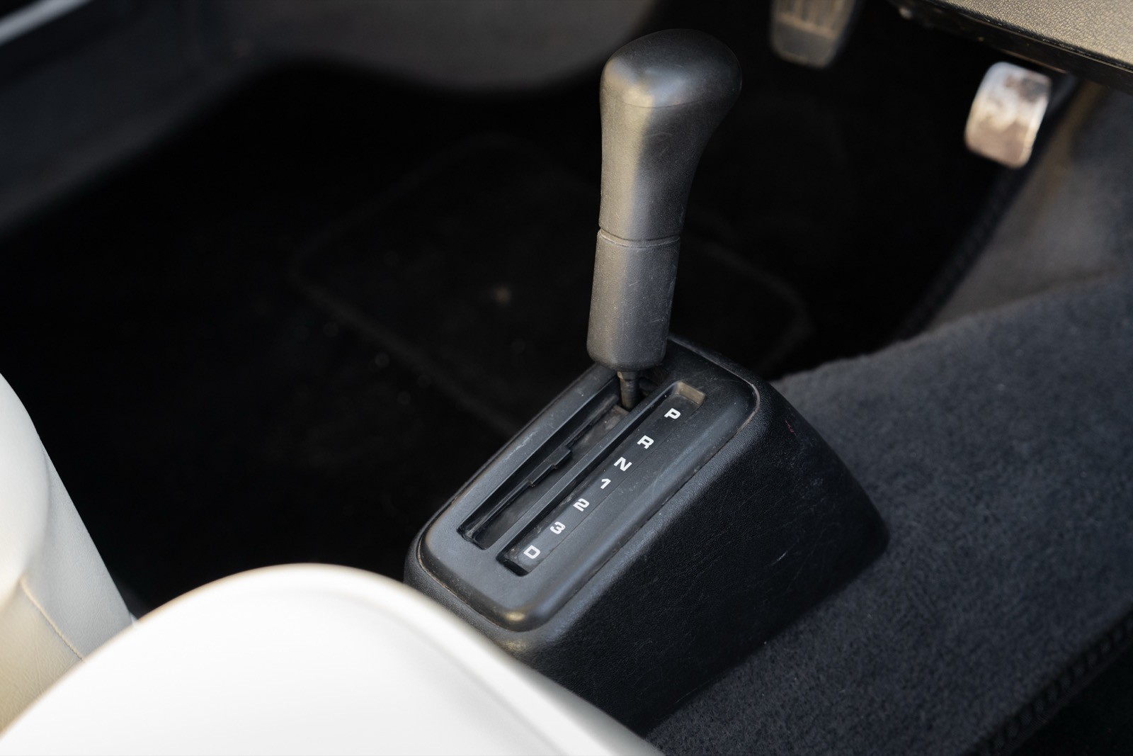 Close-up of a car's gear shift area, featuring a console with controls and a gear stick.