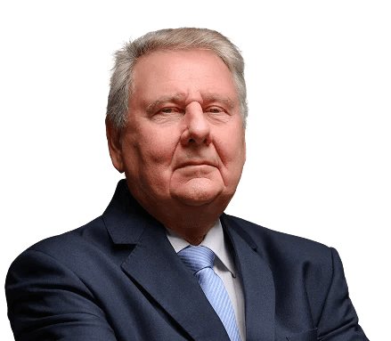 Idősebb férfi portréja sötét öltönyben, keresztbe tett karral.