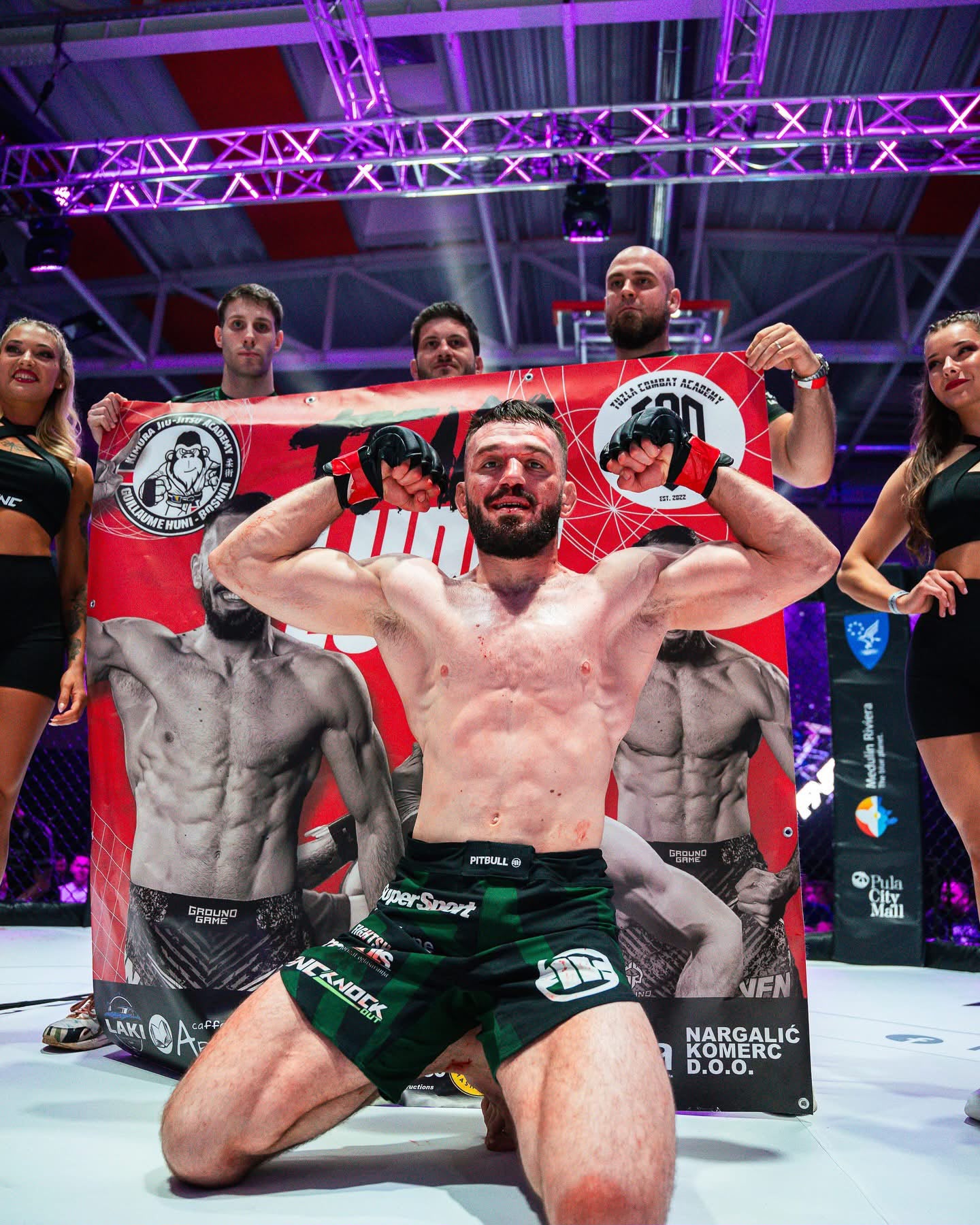 Ramiz slavi pobjedu podignutih pesnica ispred bannera Tuzla Combat Academy nakon meča u Hrvatskoj.