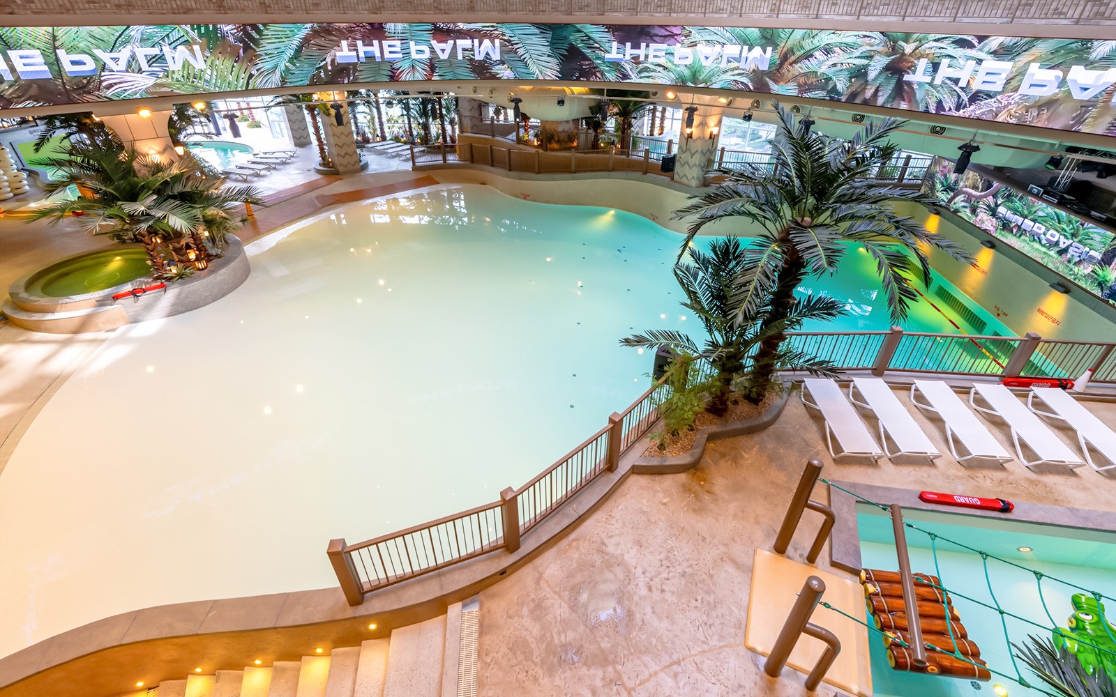 Indoor wave pool at Club D Oasis, surrounded by palm trees and LED screen.