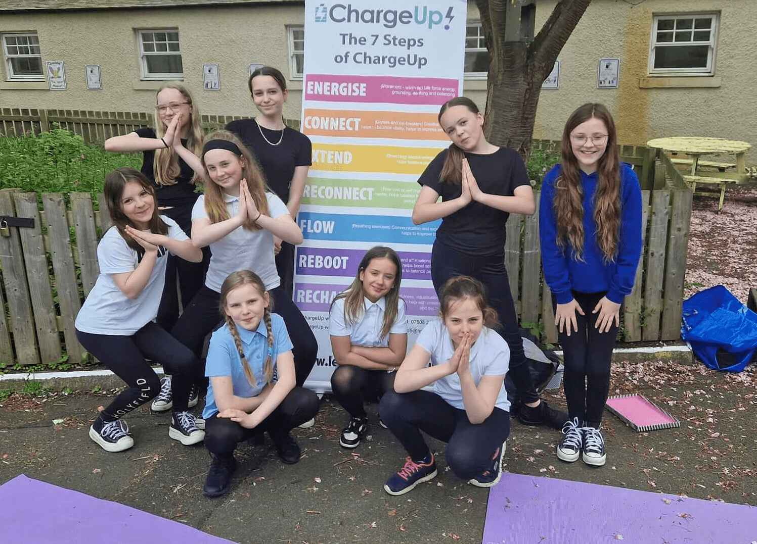 Group of young people posing for a photo standing around a banner