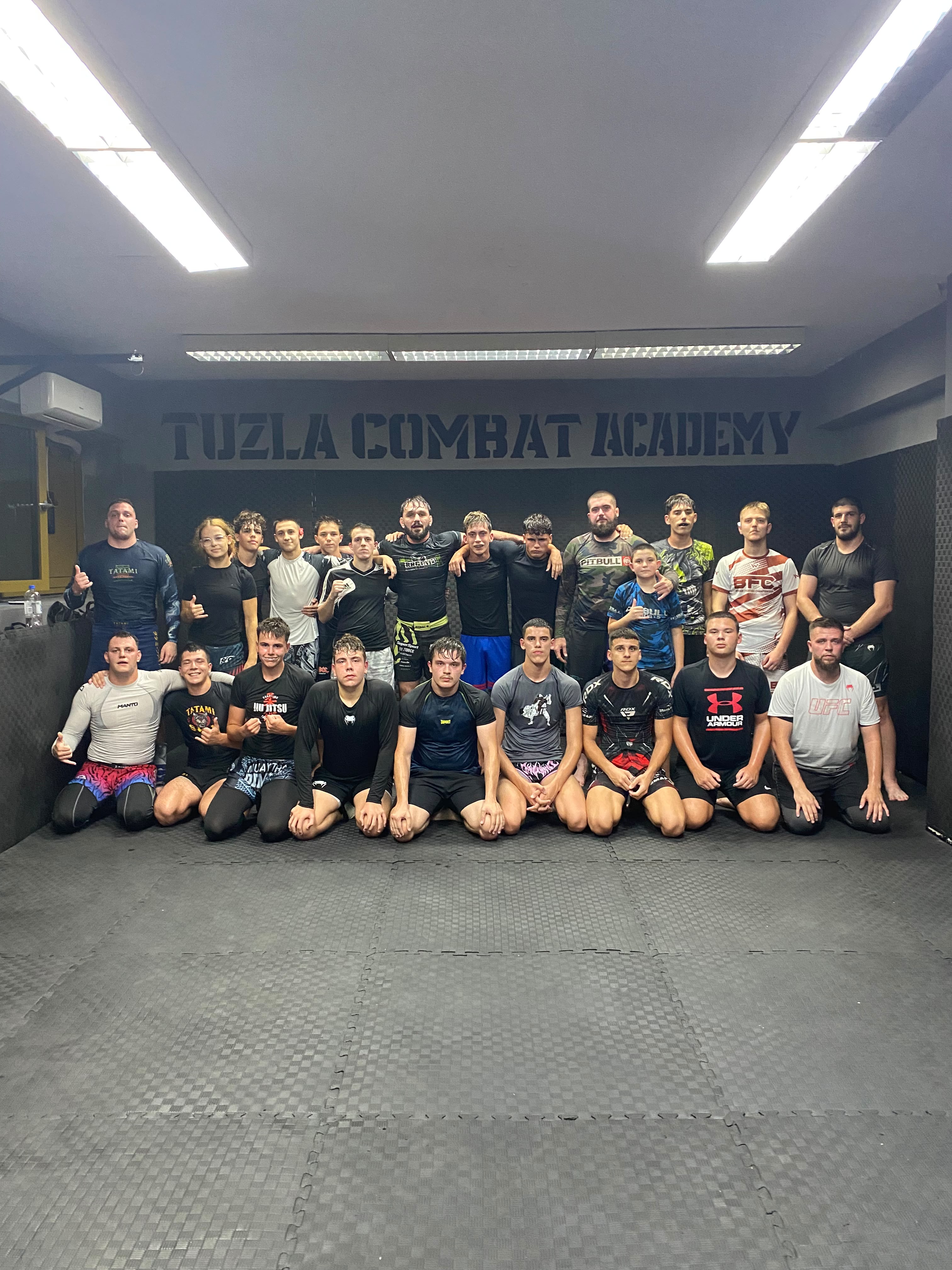 Članovi i treneri Tuzla Combat Academy pozicioniraju se za grupnu fotografiju u sali akademije.