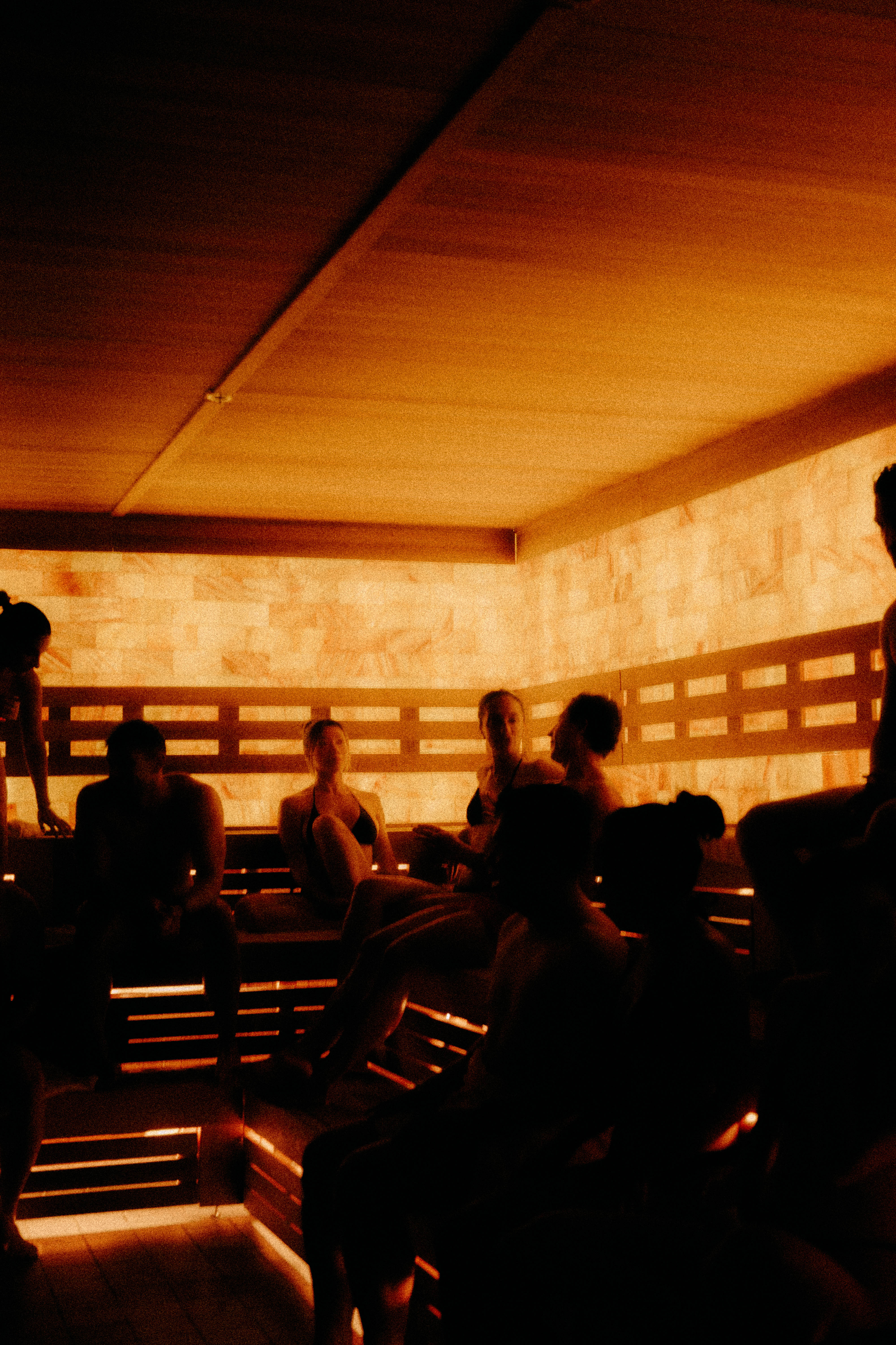 AetherHaus Aufguss session in progress with guests gathered inside a warmly lit sauna and a guide leading the ritual