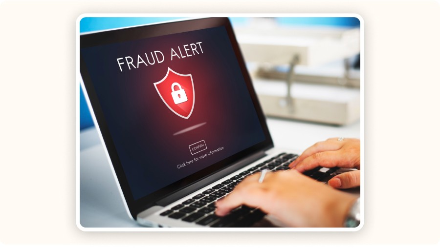 Alerte fraude affichée sur ordinateur portable, utilisateur tapant au clavier&nbsp;