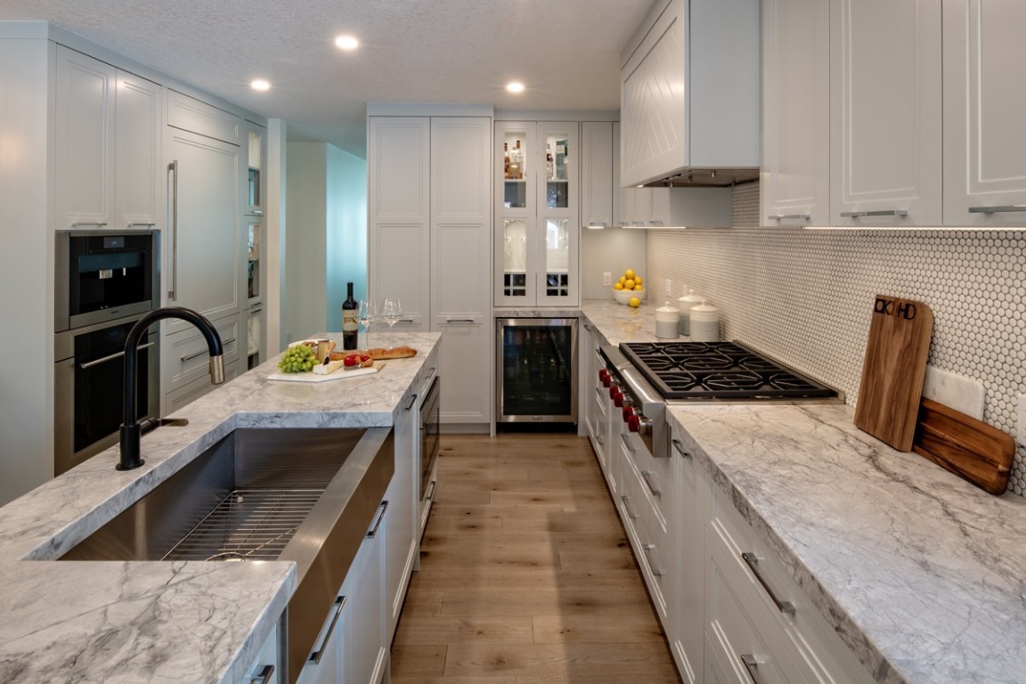 Image of Luxury kitchen design by KHD Homes featuring marble countertops, white cabinetry, and high-end appliances.