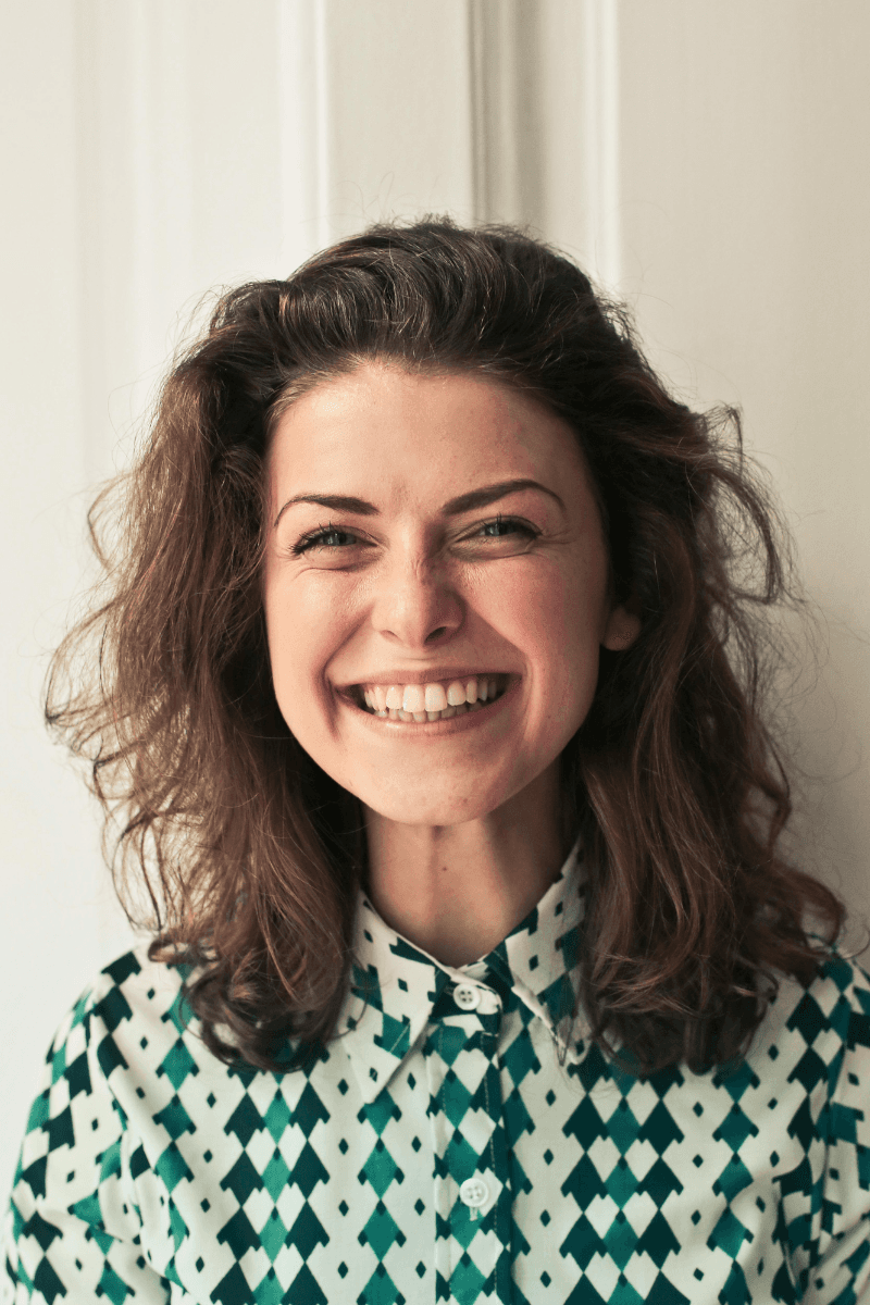 Portrait of a laughing person with curly hair wearing a white shirt