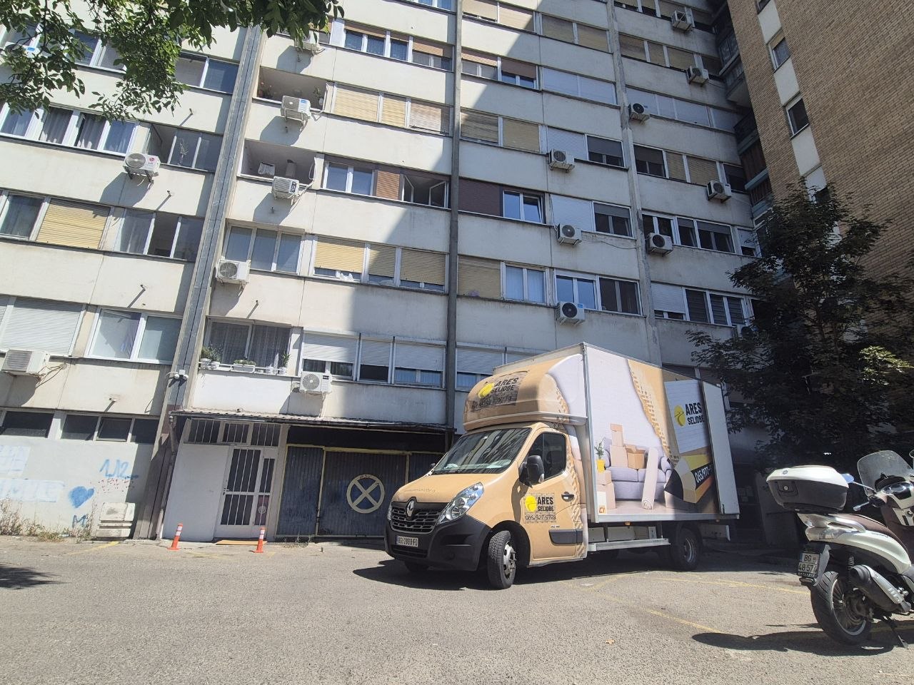 Stambena zgrada s parkiranim kamionom za selidbe ispred ulaza
