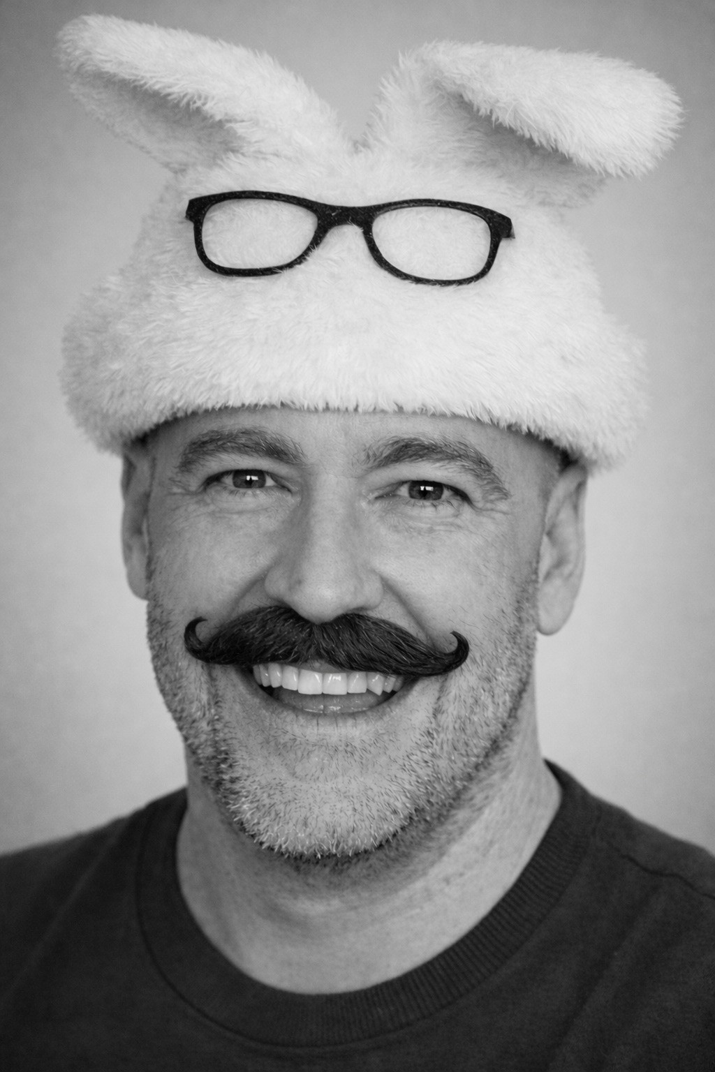 Man wearing white bunny hat with fake glasses and mustache design.