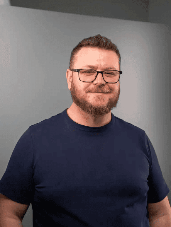 Woman with shoulder-length dark hair wearing a brown sweater, smiling at the camera.