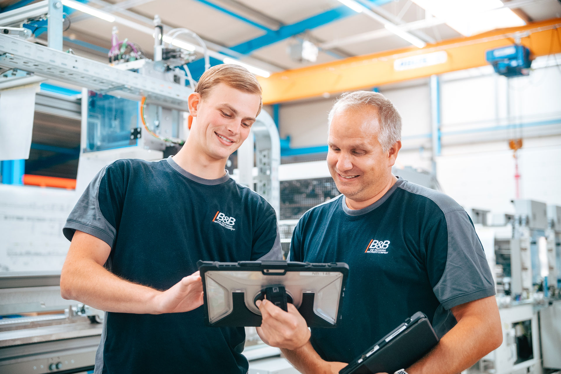 Zwei Ingenieure prüfen gemeinsam technische Daten auf einem Tablet in einer Fabrik. Maschinenbau