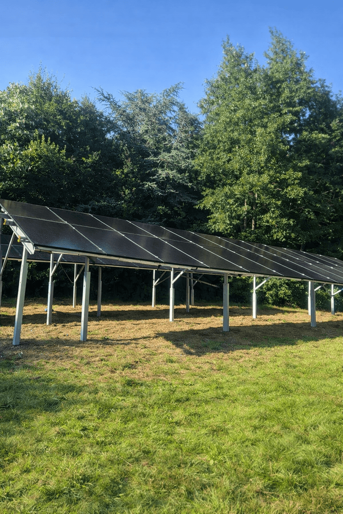 Ground mounted solar panel array installed on steel frame supports in a rural UK setting.