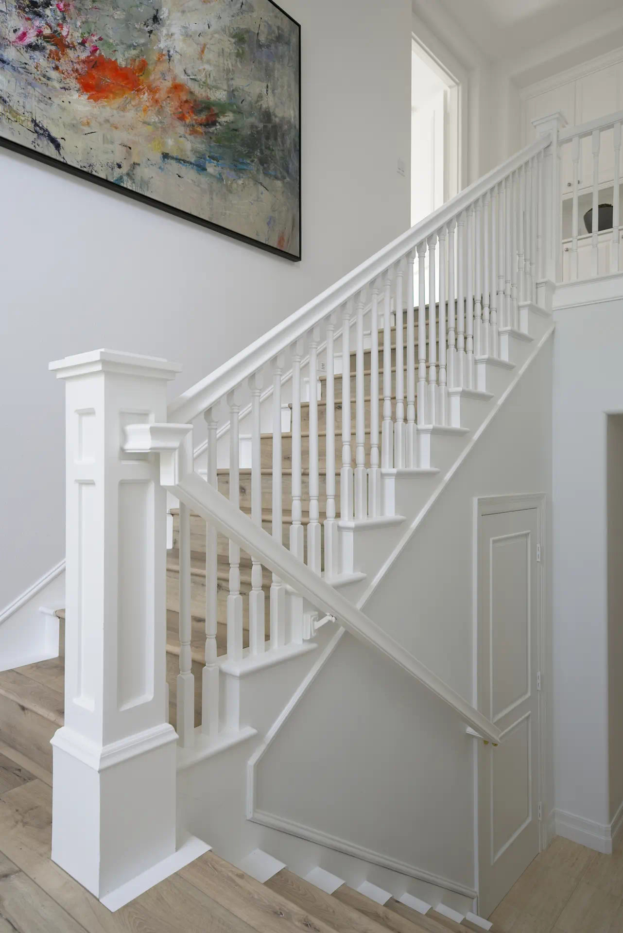 Portrait of the staircase, highlighting the oak flooring and abstract wall art, which add a modern artistic touch to this Tustin Ranch home. Photo by Todd Huge.