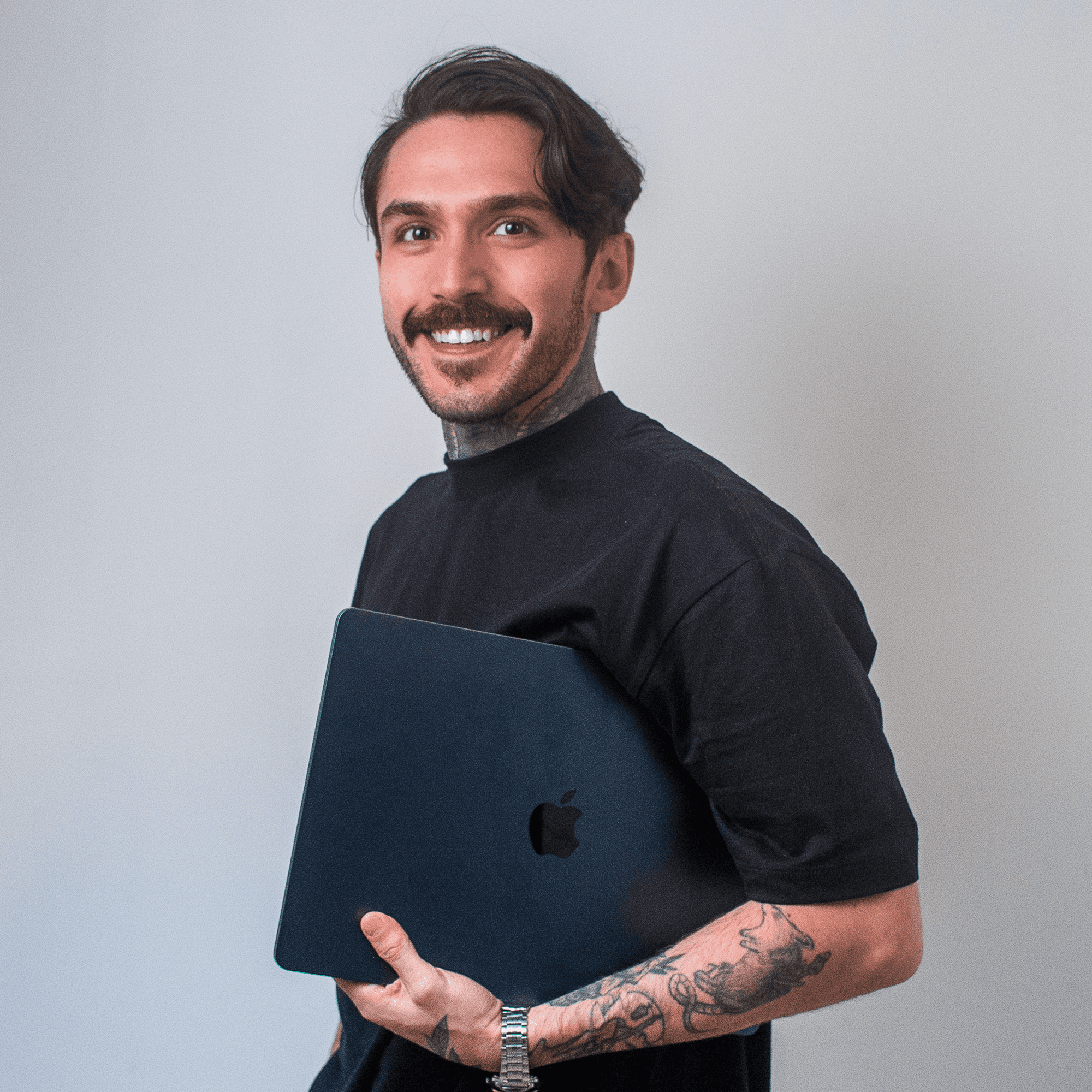 Man sitting in a dimly lit room, wearing a beige shirt and looking contemplative.
