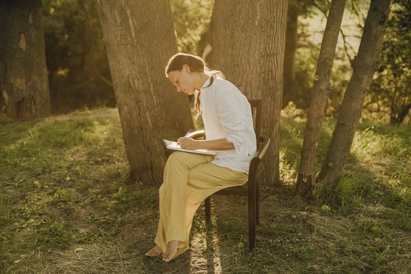 Woman in forest on chair writes letter