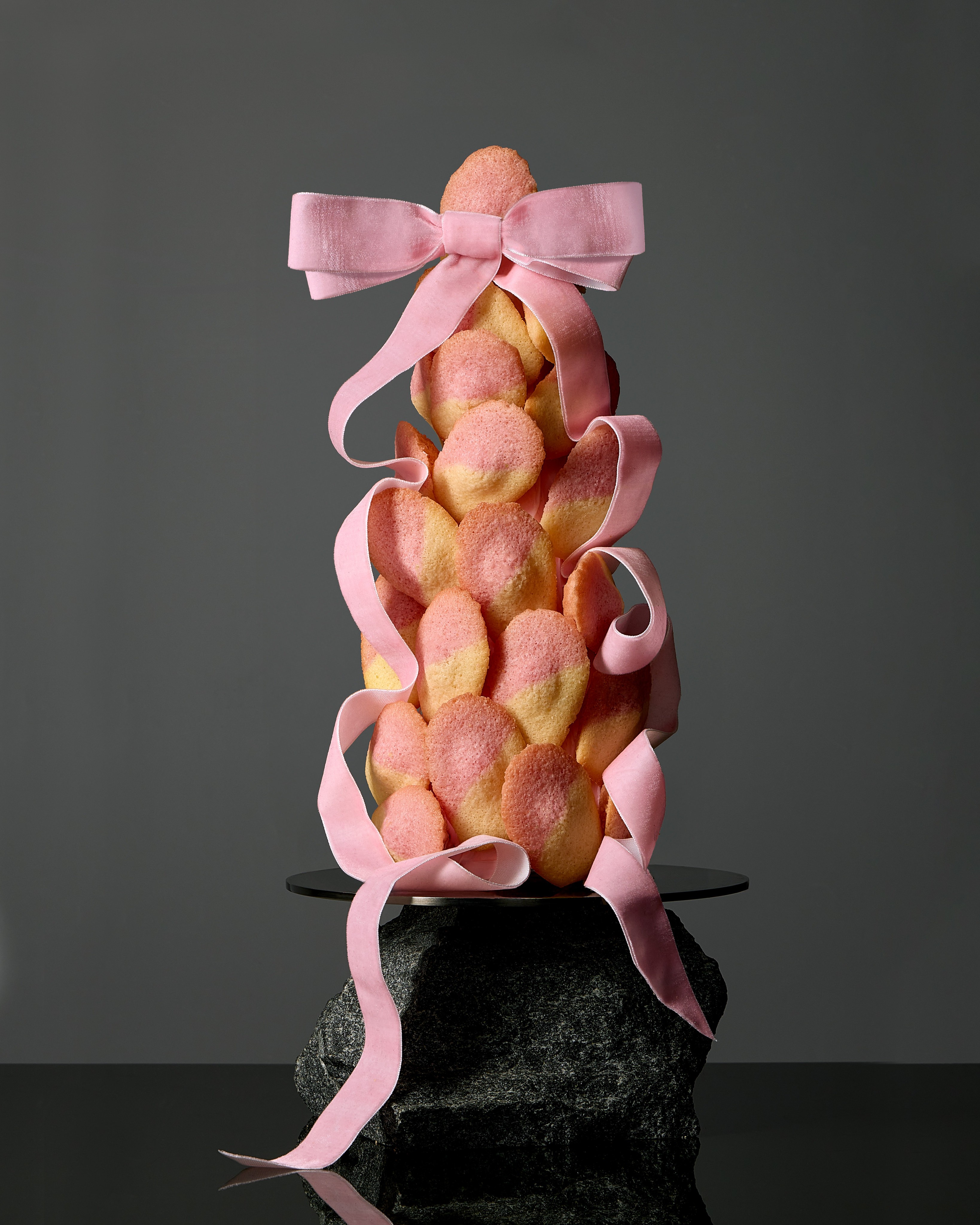 Tower of pink madeleines wrapped in velvet ribbon on a black rock