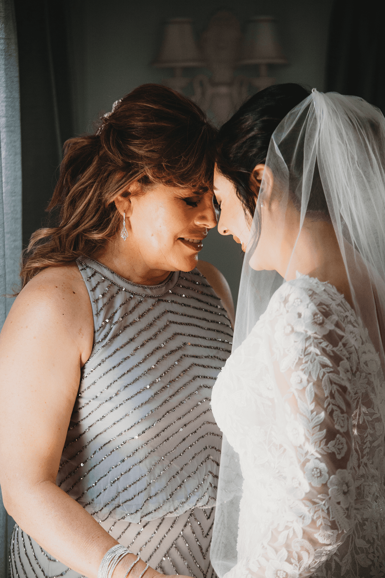 Bride and mother touching foreheads emotional getting ready moment