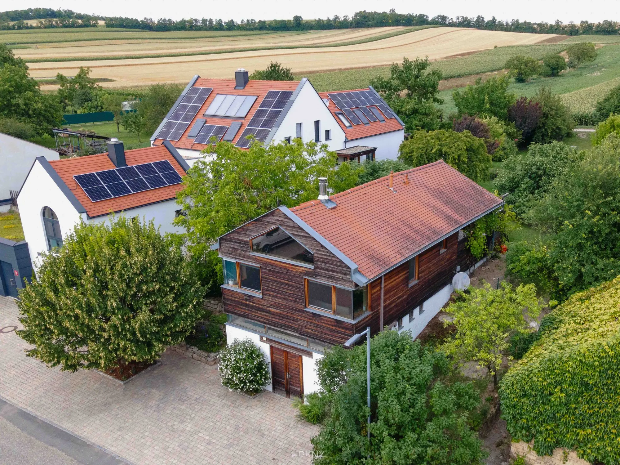 Luftaufnahme des Ferienhauses „Das Haus im Grünen“ in Gallbrunn mit Holzfassade und Ziegeldach, umgeben von Gärten und Feldern